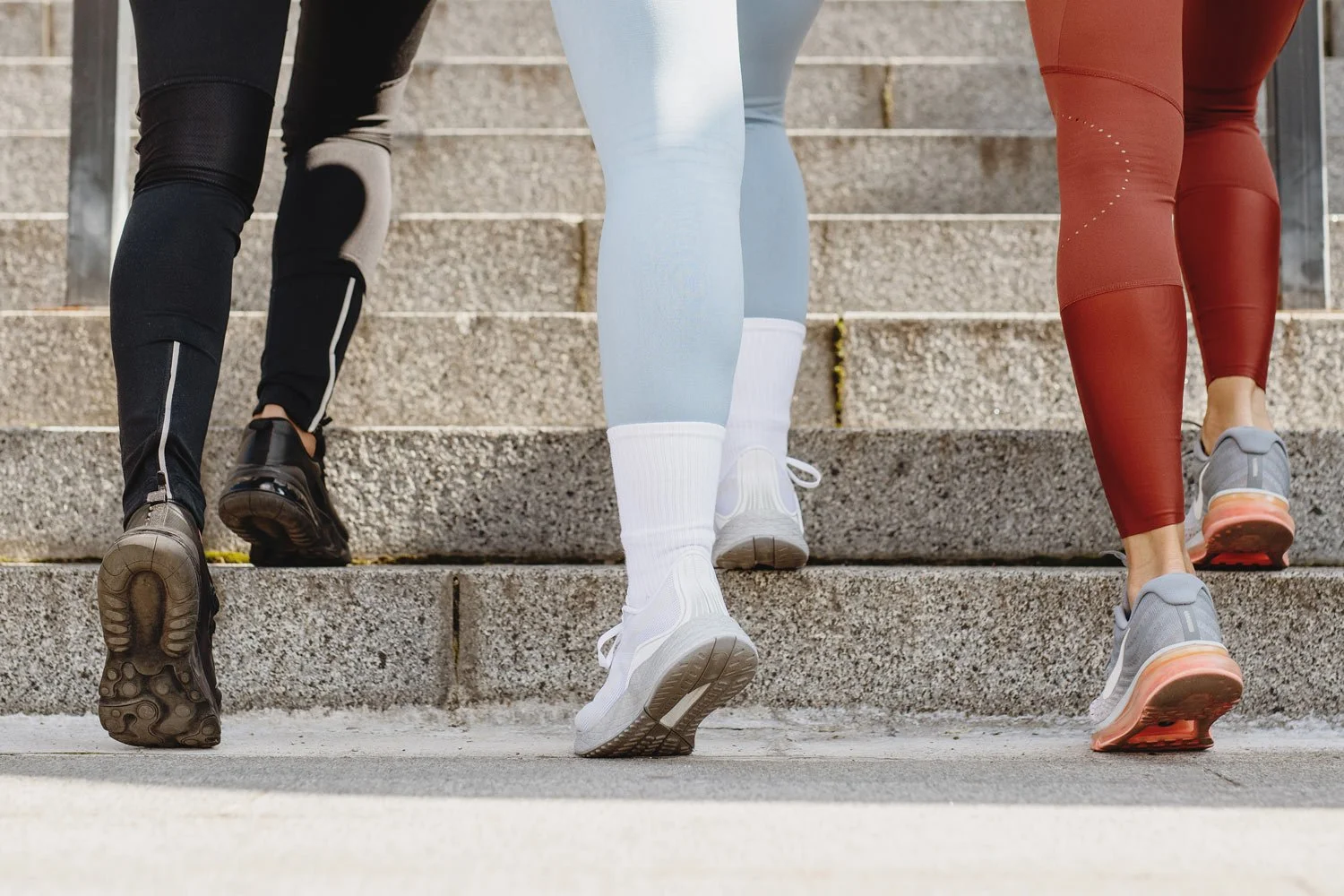 Close up of three women in workout clothes walking up stairs in sync