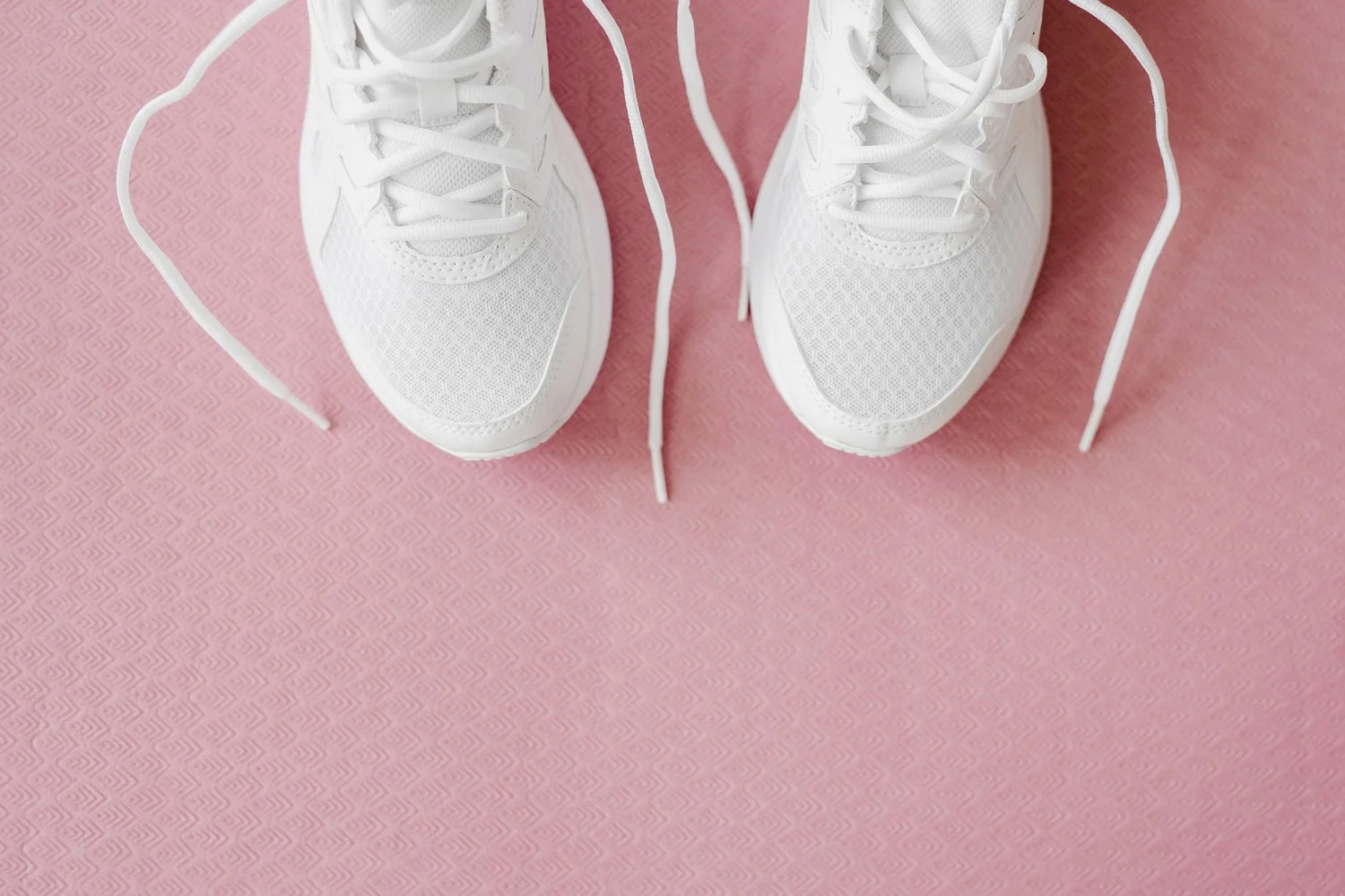 White sneakers sitting on pink yoga mat