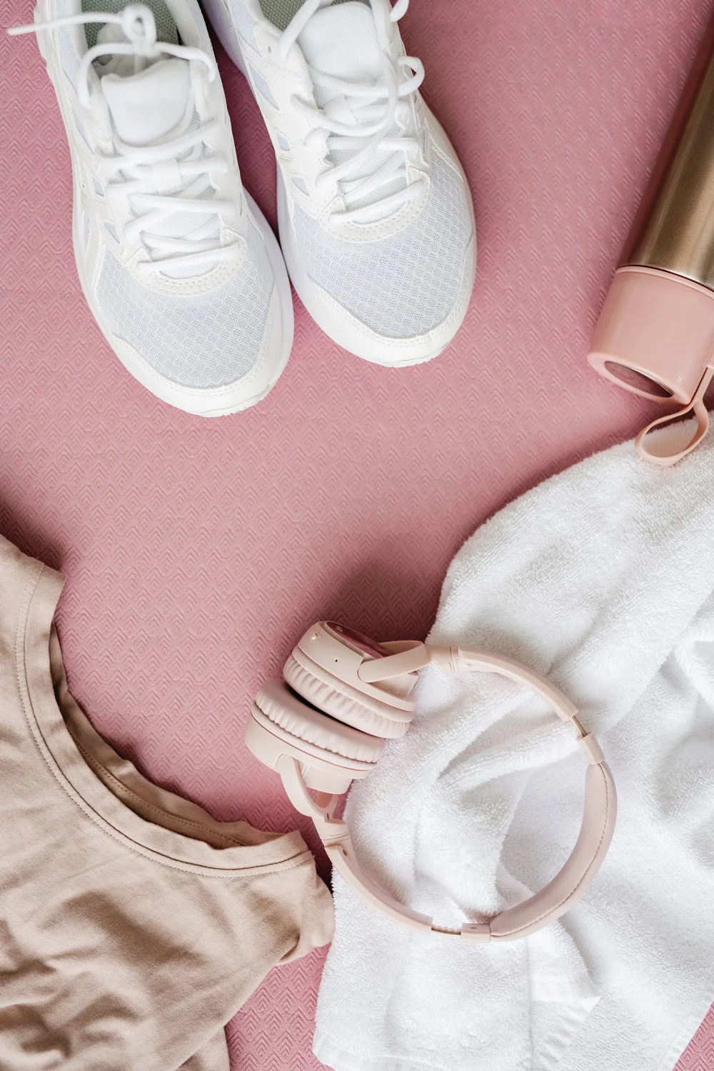 White tennis shoes sitting on top of a pink yoga mat and a water bottle