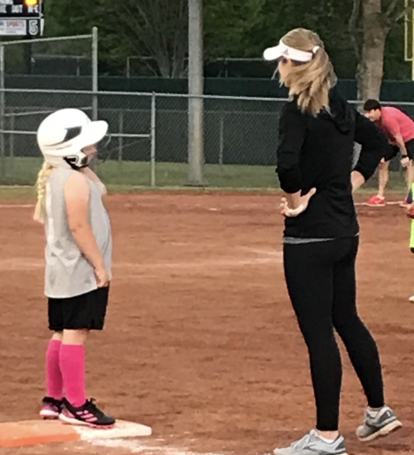 A young softball player standing on base during a game