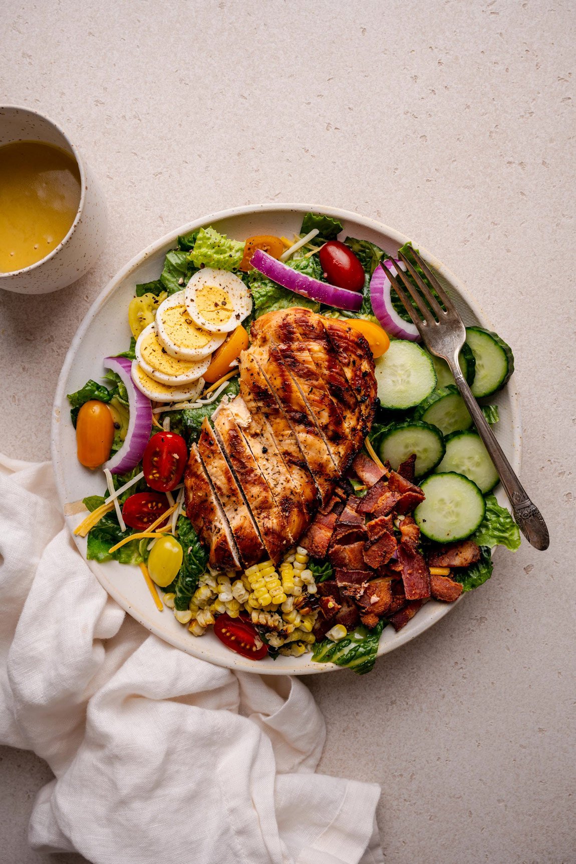A fresh salad with grilled chick, boiled eggs, cucumbers and tomatoes with a fork