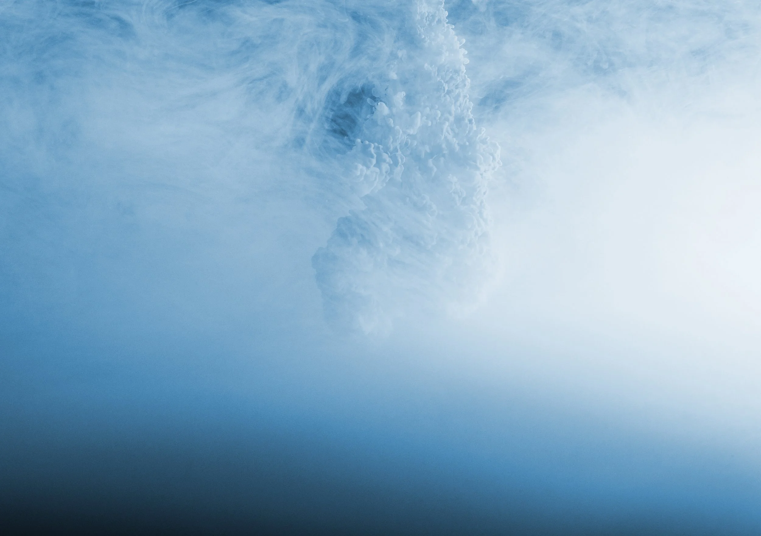 A large explosion or cloud of smoke and steam against a blue sky.