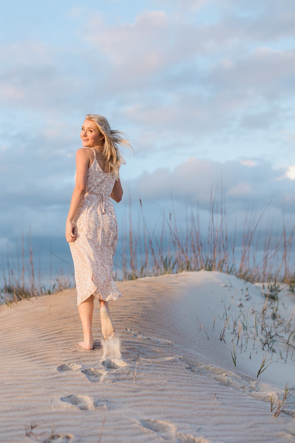 Senior girl running in the sand dunes in St. Augustine, FL