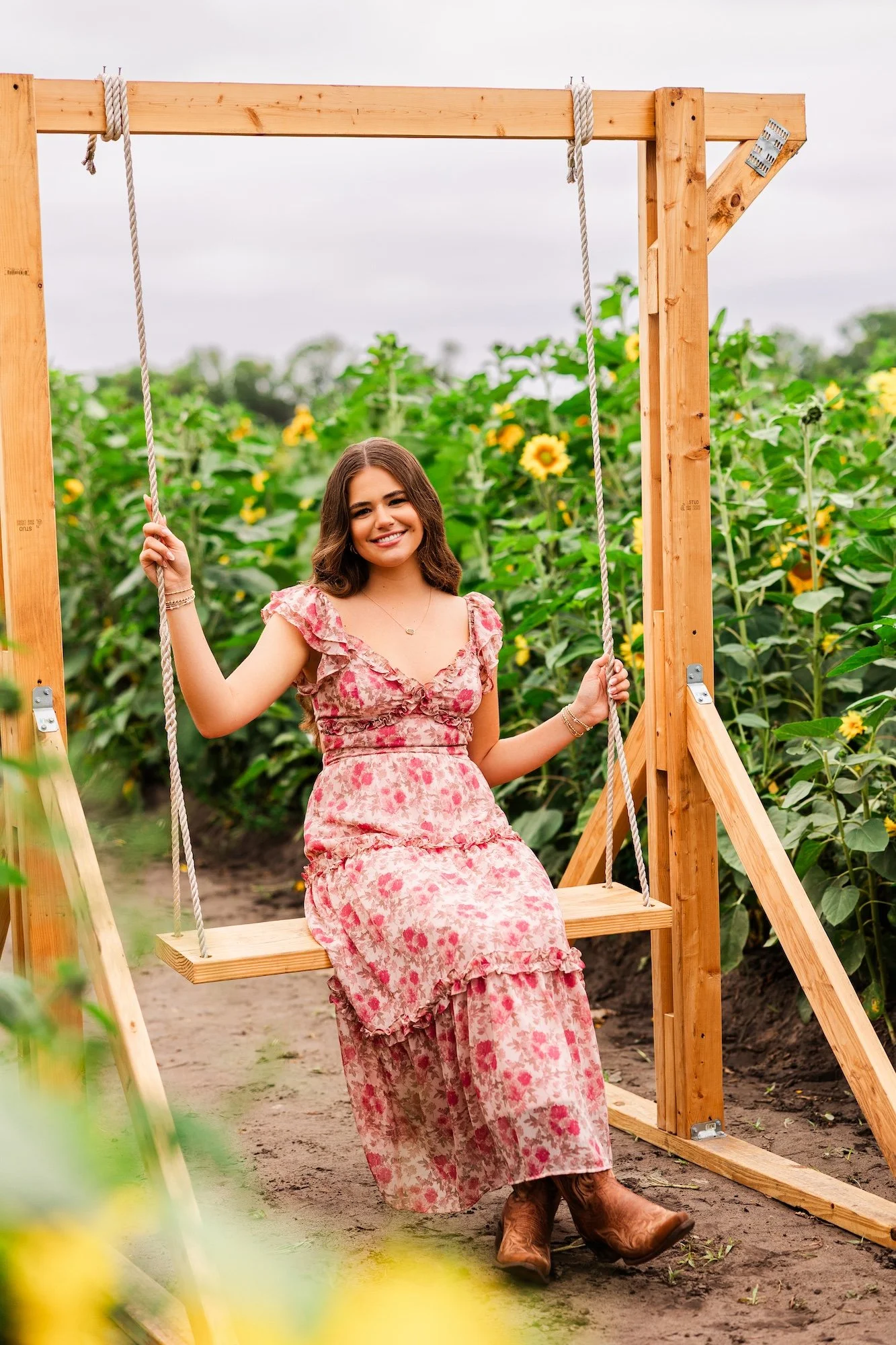 high school senior on a swing surrounded by sunflower field
