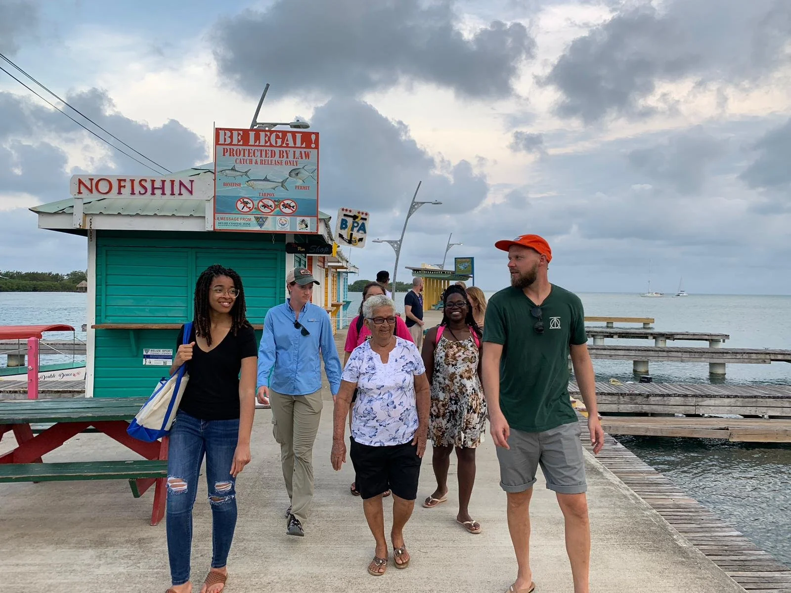 Group of six people walking along a dock by the water, on the job site, working with the community to co-develop proficient in community-engaged engineering.
