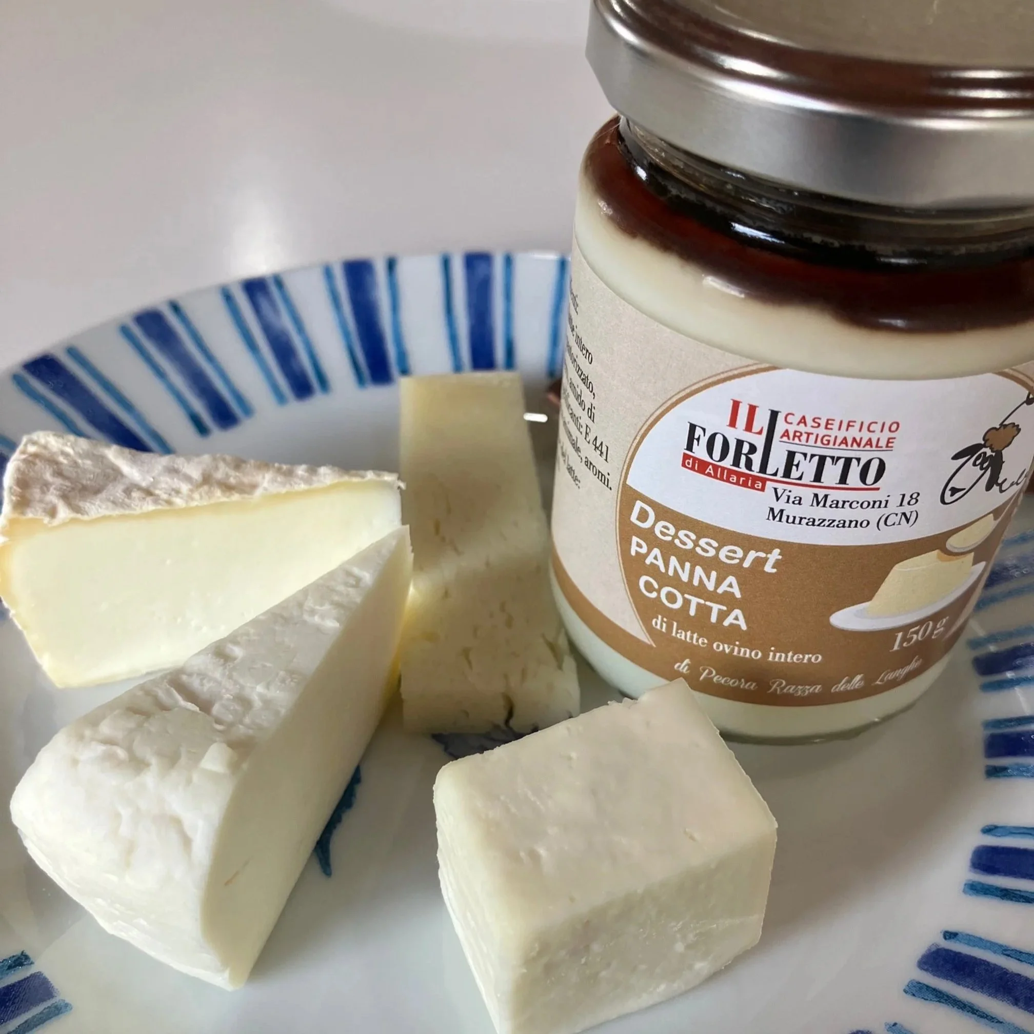 Een bord met verschillende soorten witte kaas waaronder de Tuma uit Murazzano en een potje van Il Forletto met pistache-olie saus.