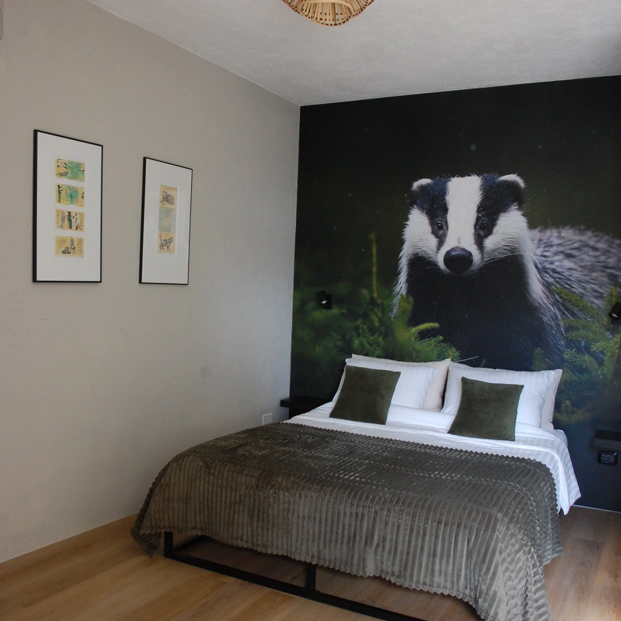 Slaapkamer met bed, groene kussens, een muurdecoratie van een das en een ingelijste afbeelding aan de muur.