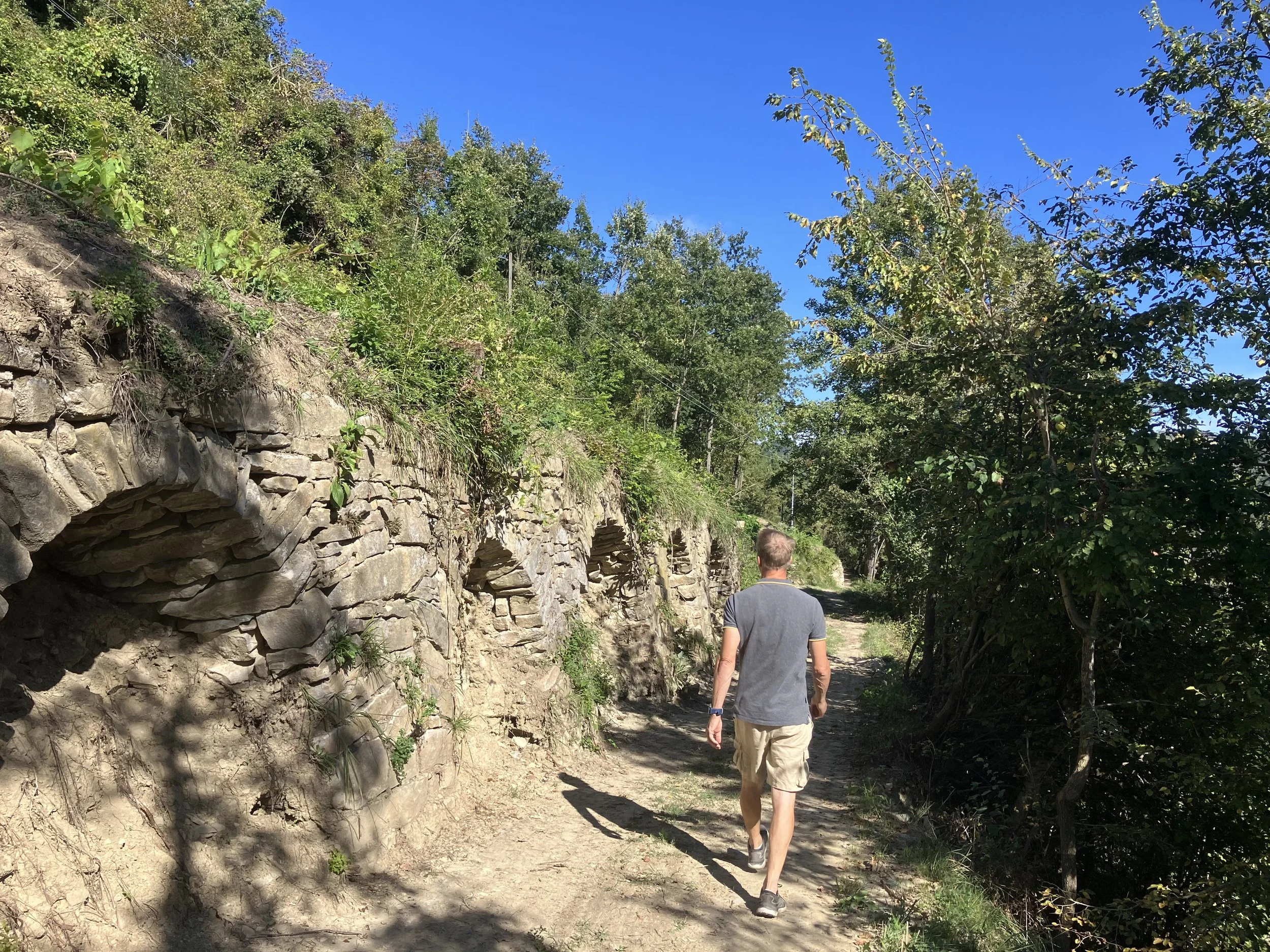 Wandelaar op pad langs oude stenen muur