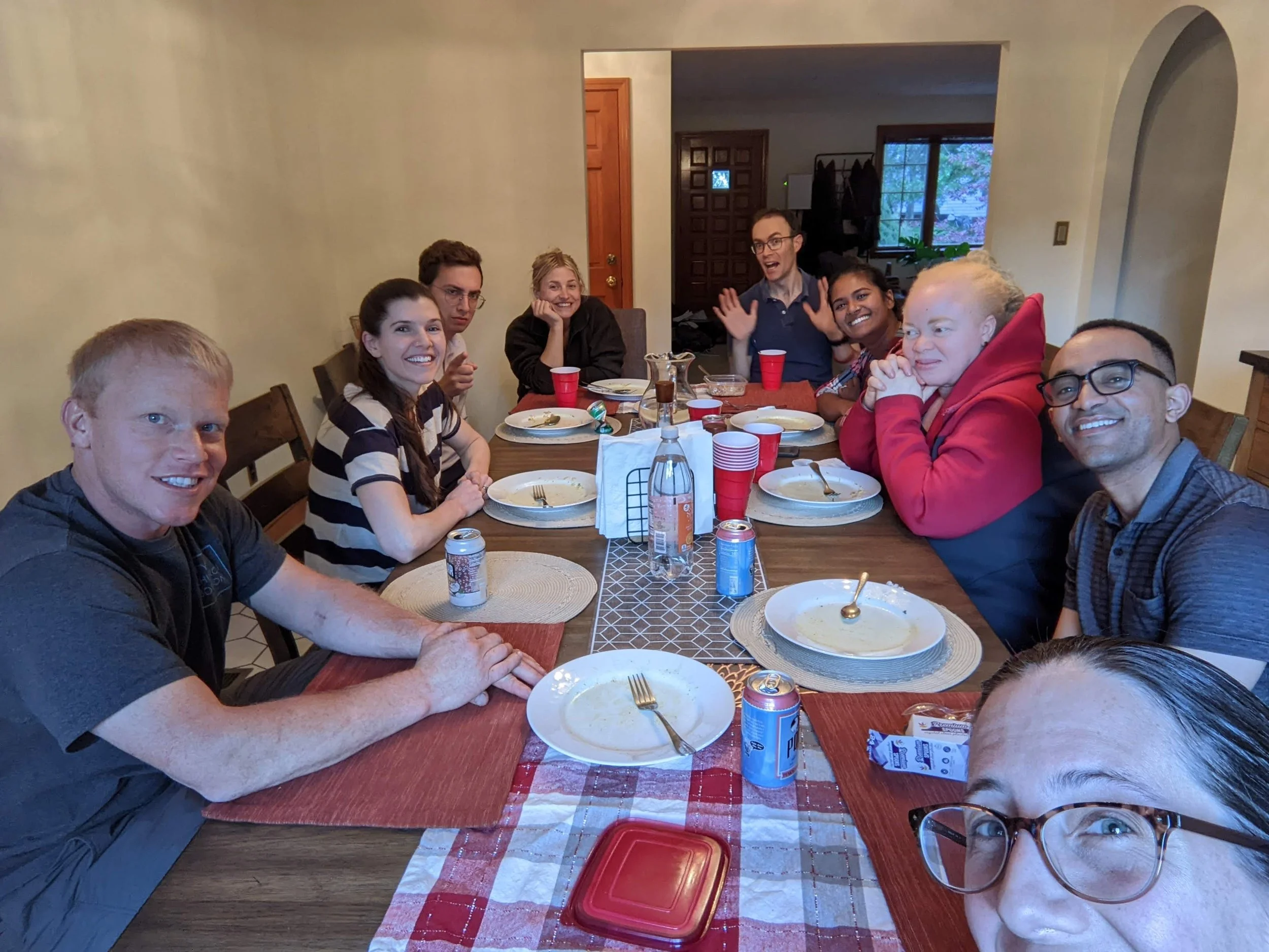 A family gathered around a dining table after a meal, smiling and enjoying each other's company in a cozy home dining area.