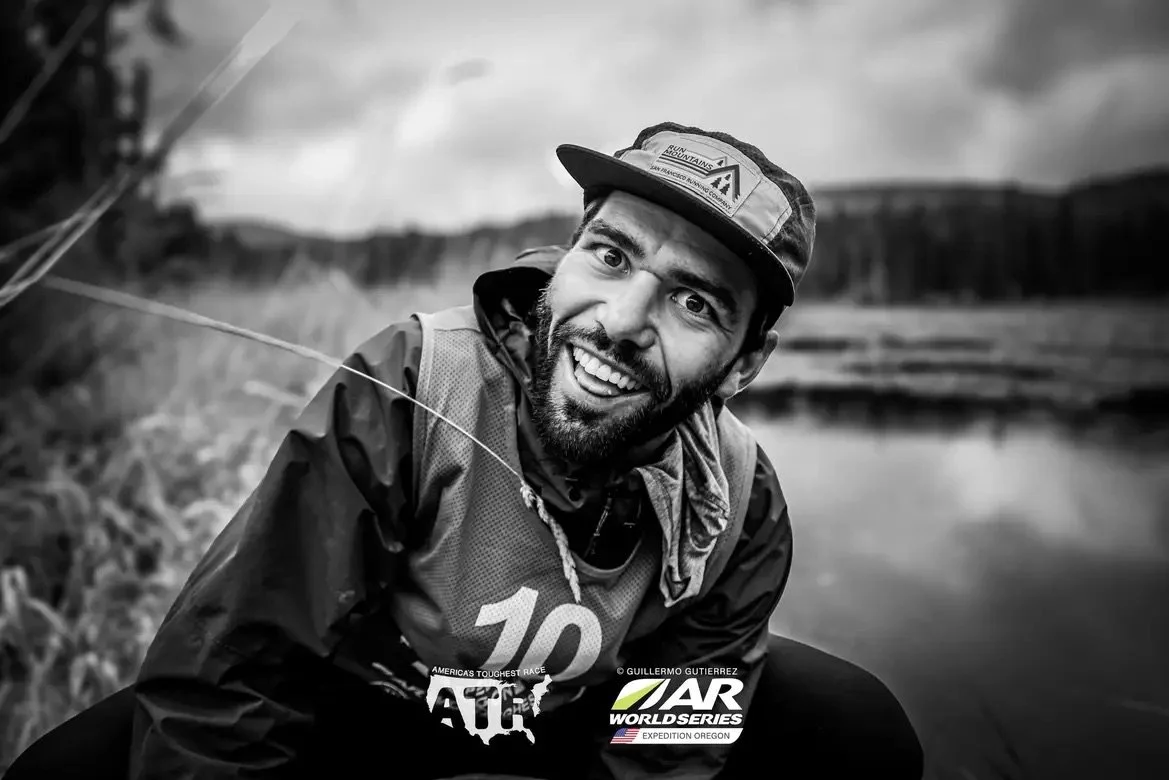 A smiling man with a beard and cap in outdoor setting near water, participating in the AR World Series Expédition Oregon event.