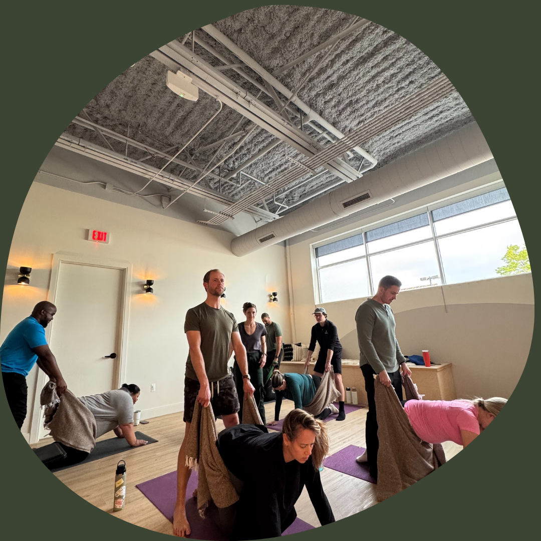 Indoor prenatal yoga or fitness class with children and adults seated on yoga mats, participating while one instructor or parent gestures among the group.