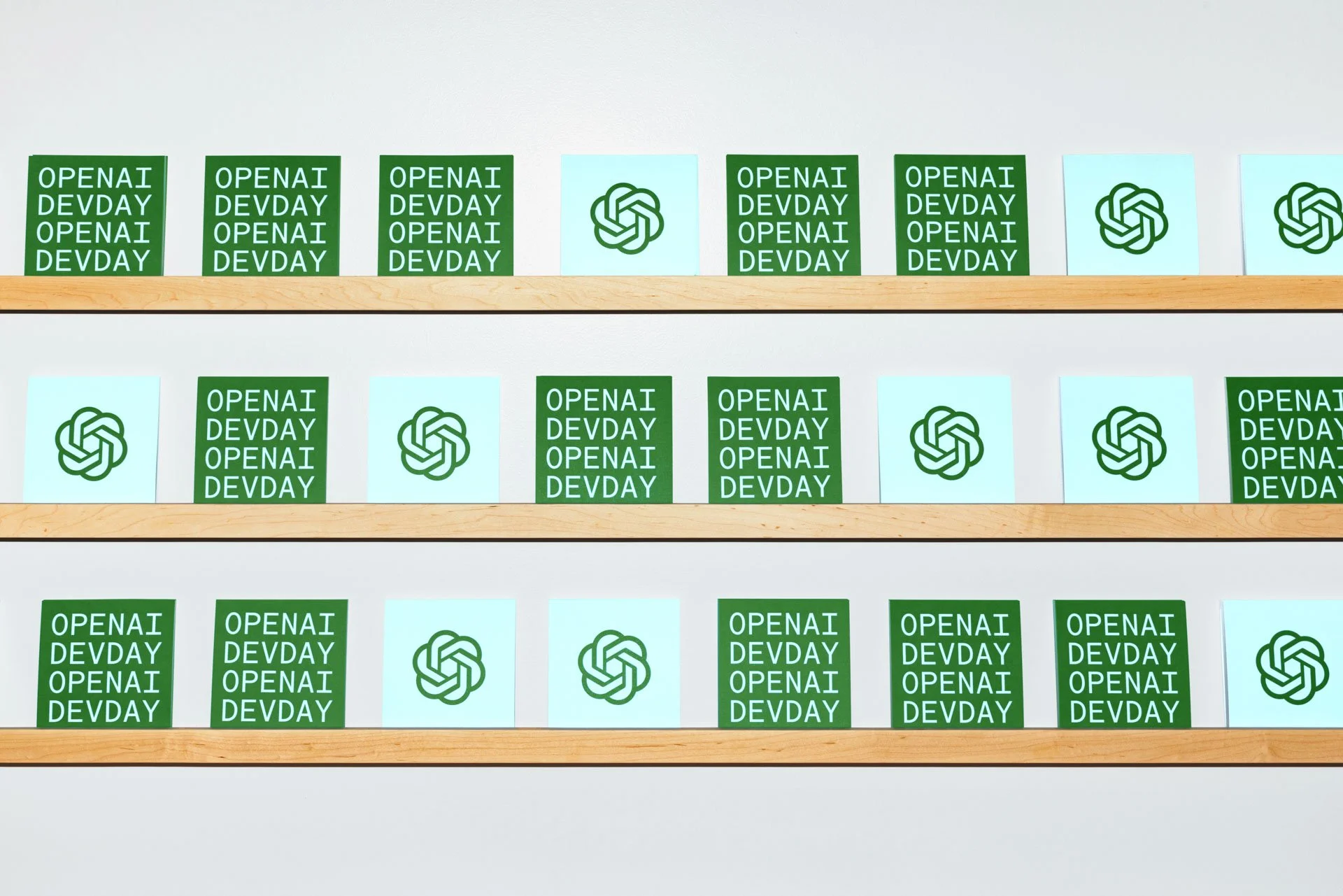 Shelf with cards featuring green and light blue background, displaying the words 'OPENAI DEV DAY' and the OpenAI logo.