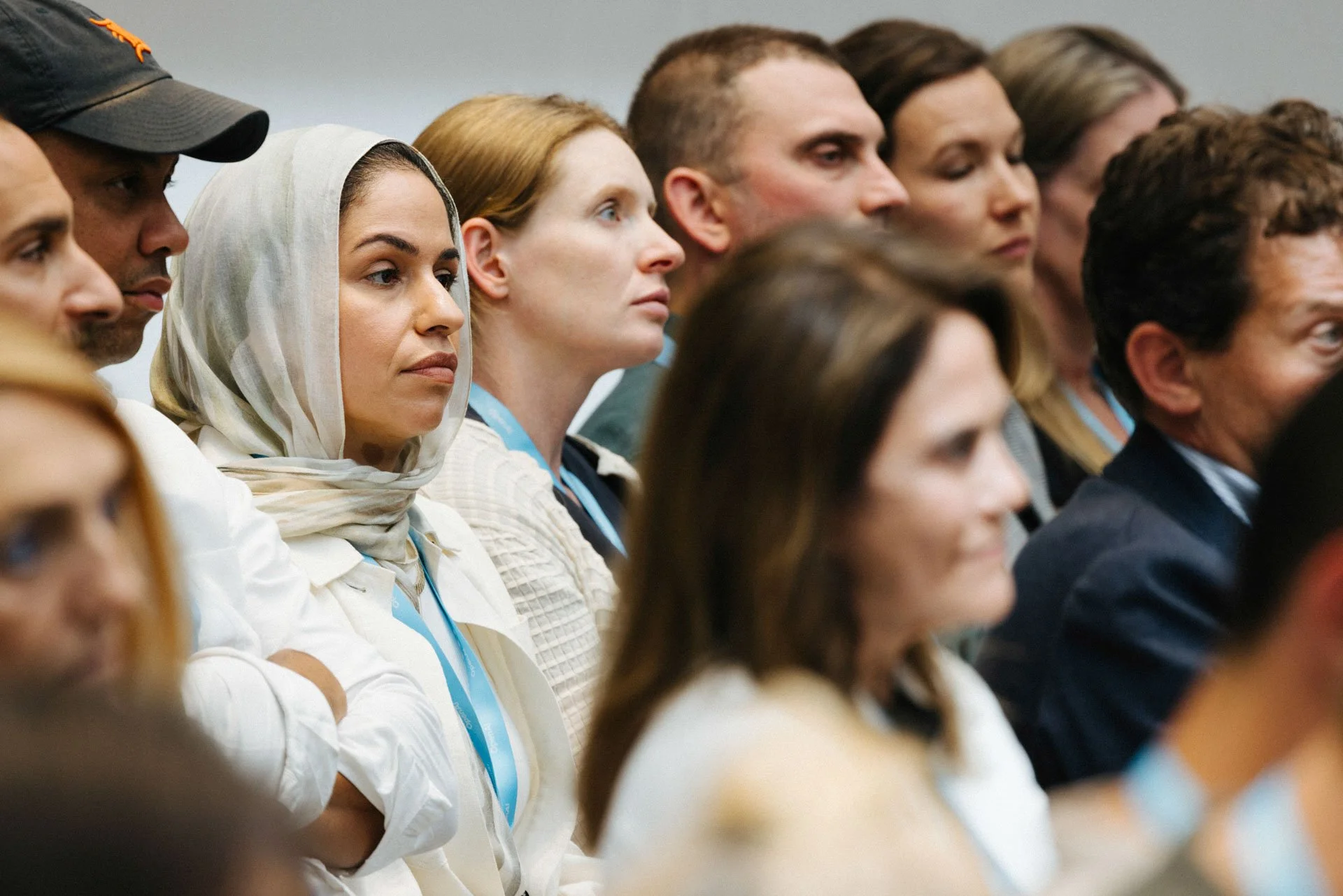 A diverse group of people attentively listening at a conference or seminar, seated side by side.