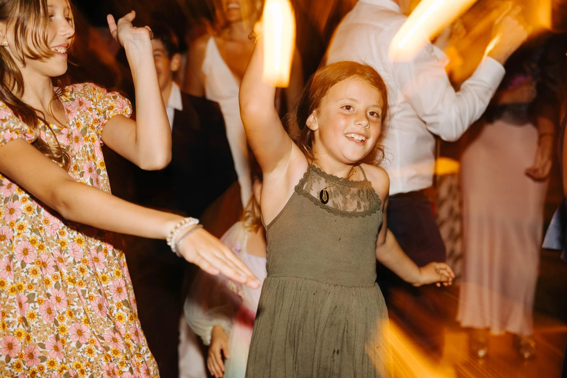 Young girl dancing and smiling at a celebration or party with others around her.