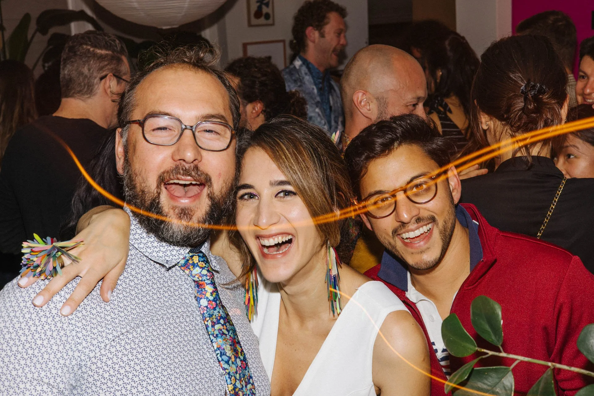 Group of people celebrating at a party, smiling, with colorful decorations and a lively atmosphere.