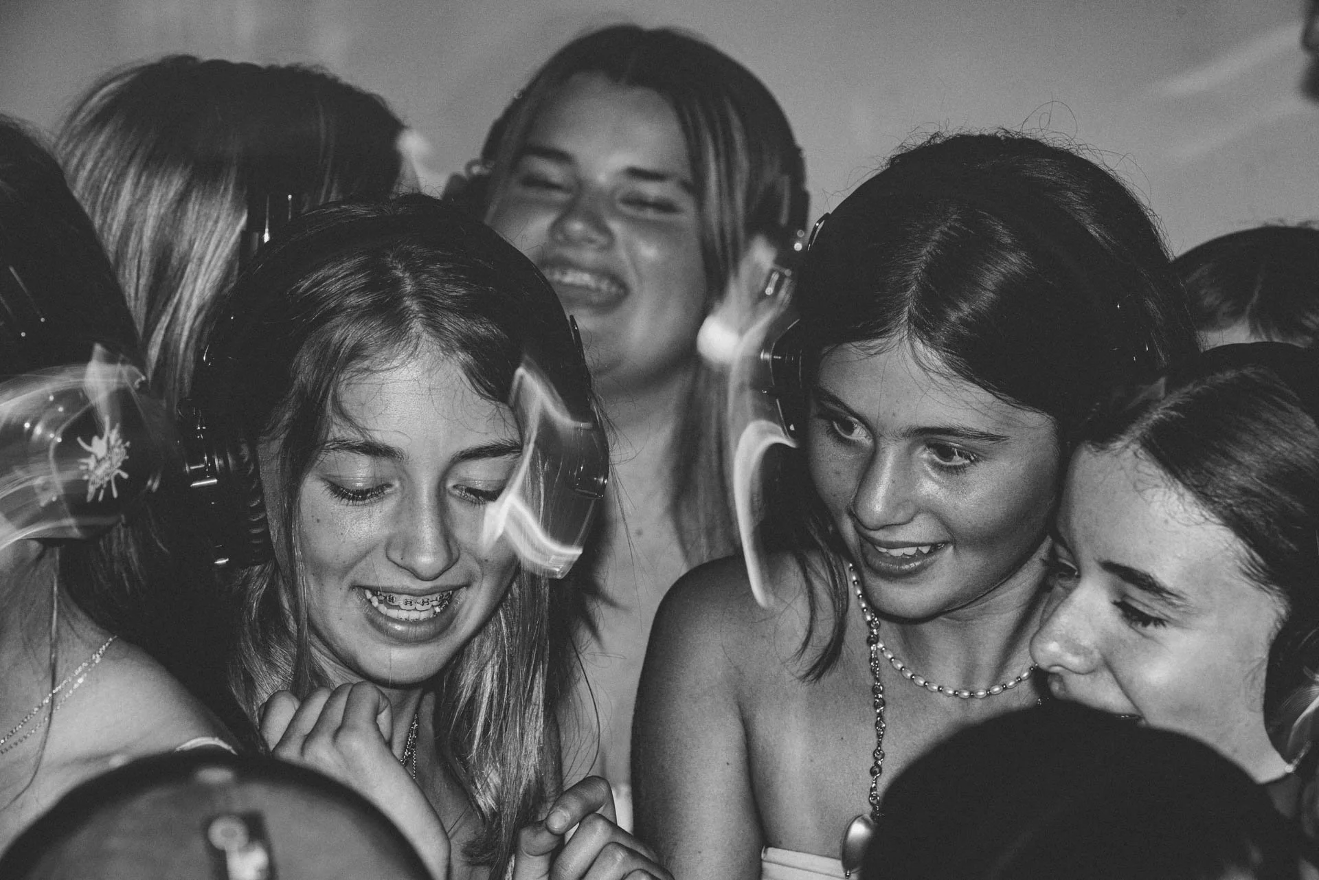 Group of young women wearing headphones at a party, enjoying music together.