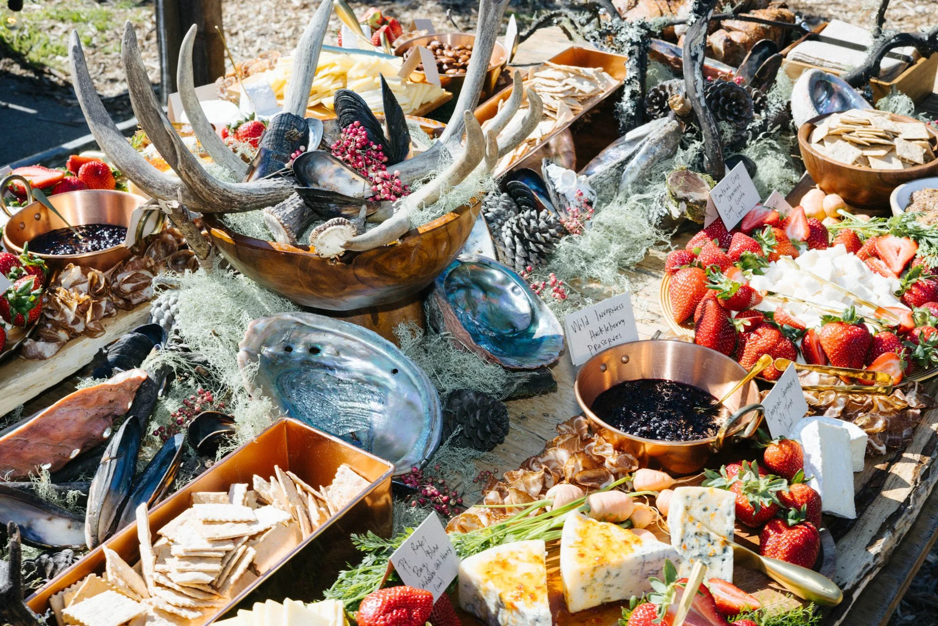 A variety of fresh seafood, strawberries, and cheeses displayed on a rustic wooden table.