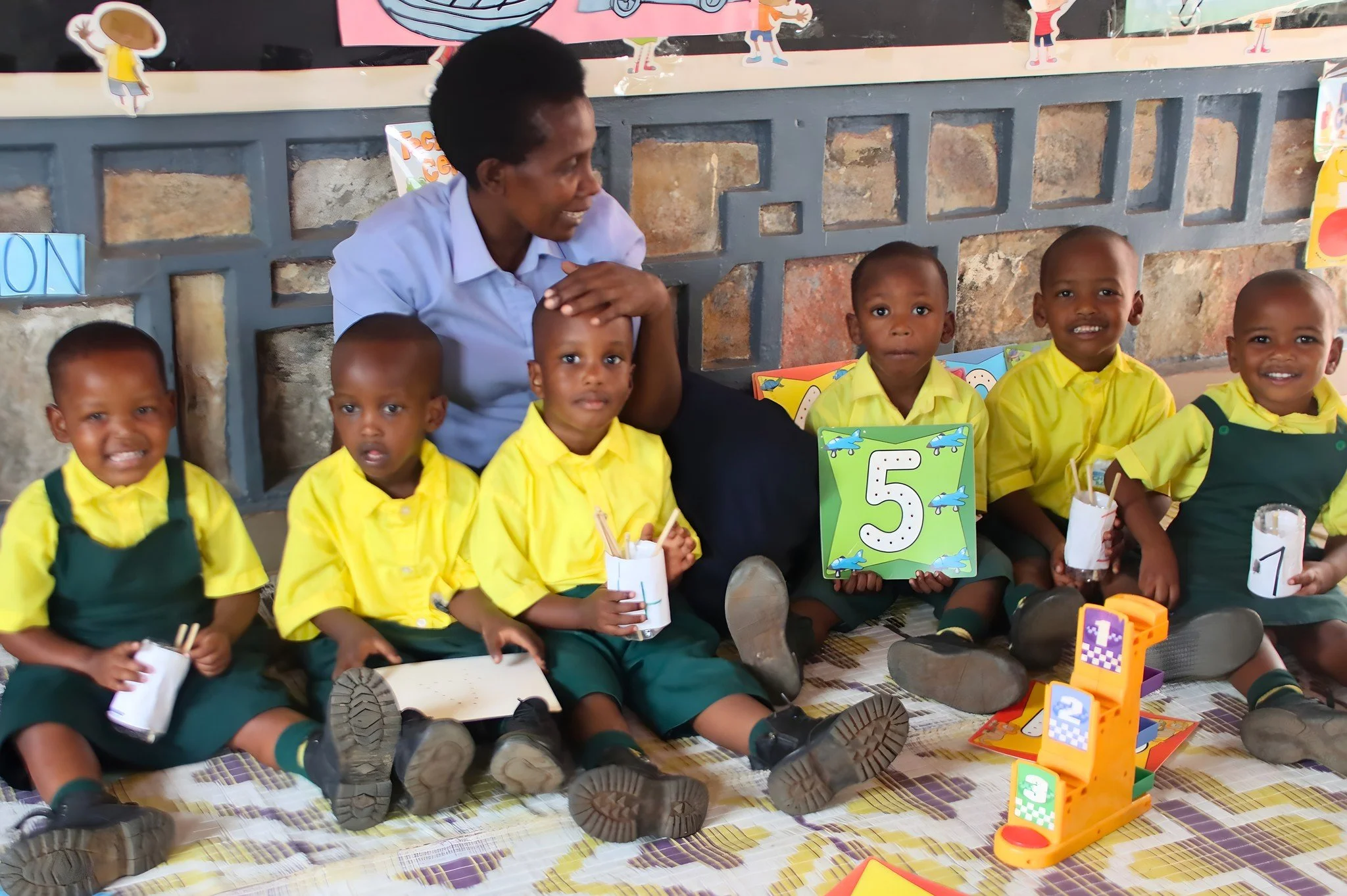 Anna Ngamije and her RCCS Early Childhood Development students are busy learning about numbers. Children's ability to understand numbers and counting improves significantly between the ages of two and four. By ages four to six, children can match the
