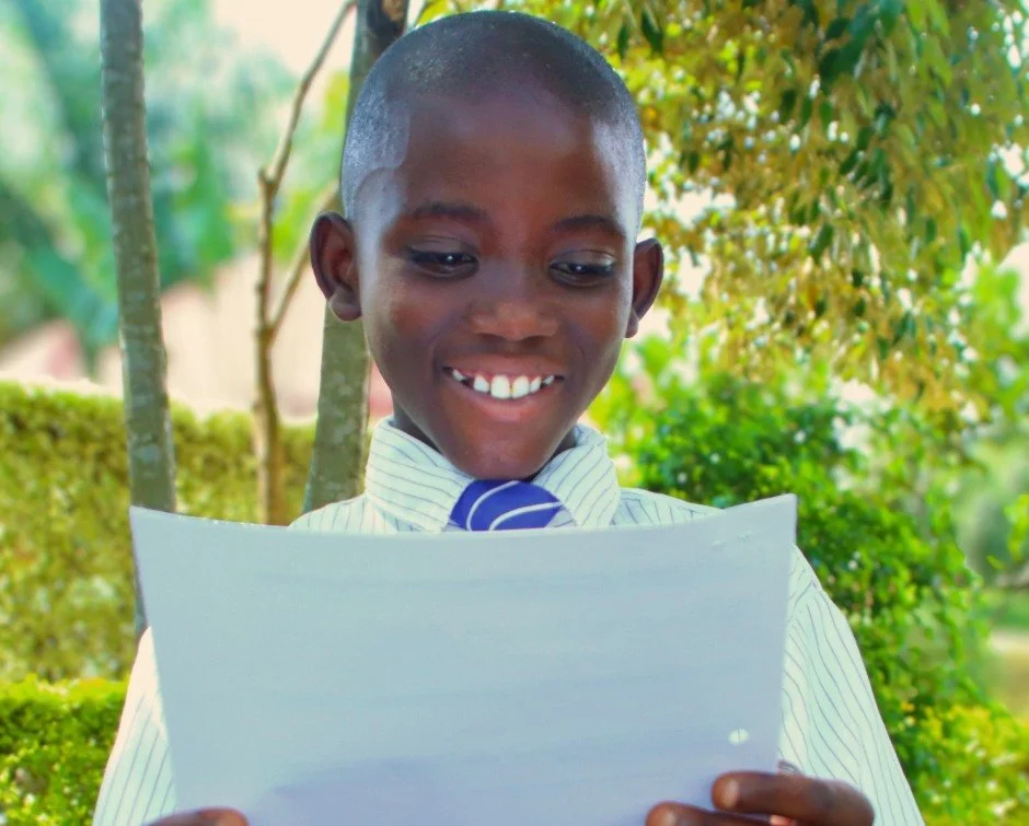 Fils held the letter with both hands.

He smiled as he read.

Then he kept reading.

And reading.

Not once did he look up.

For a few minutes, everything else seemed to disappear.

Someone across the world had written to him.

Someone knew his name.