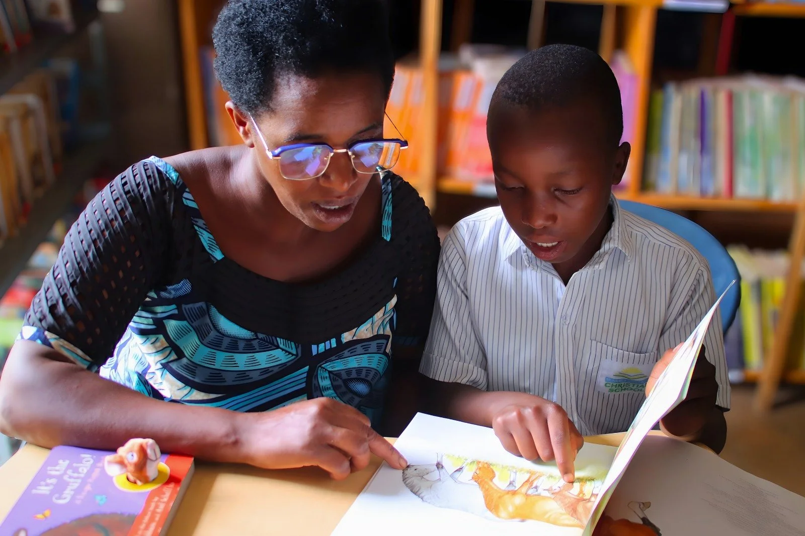 "Mom, listen to this."

Bruno is reading one of his favorite books with his mother.

Moments like this are why Rwanda Children has invested in two well-stocked libraries on our campus.

In our part of Rwanda, there are no public libraries a