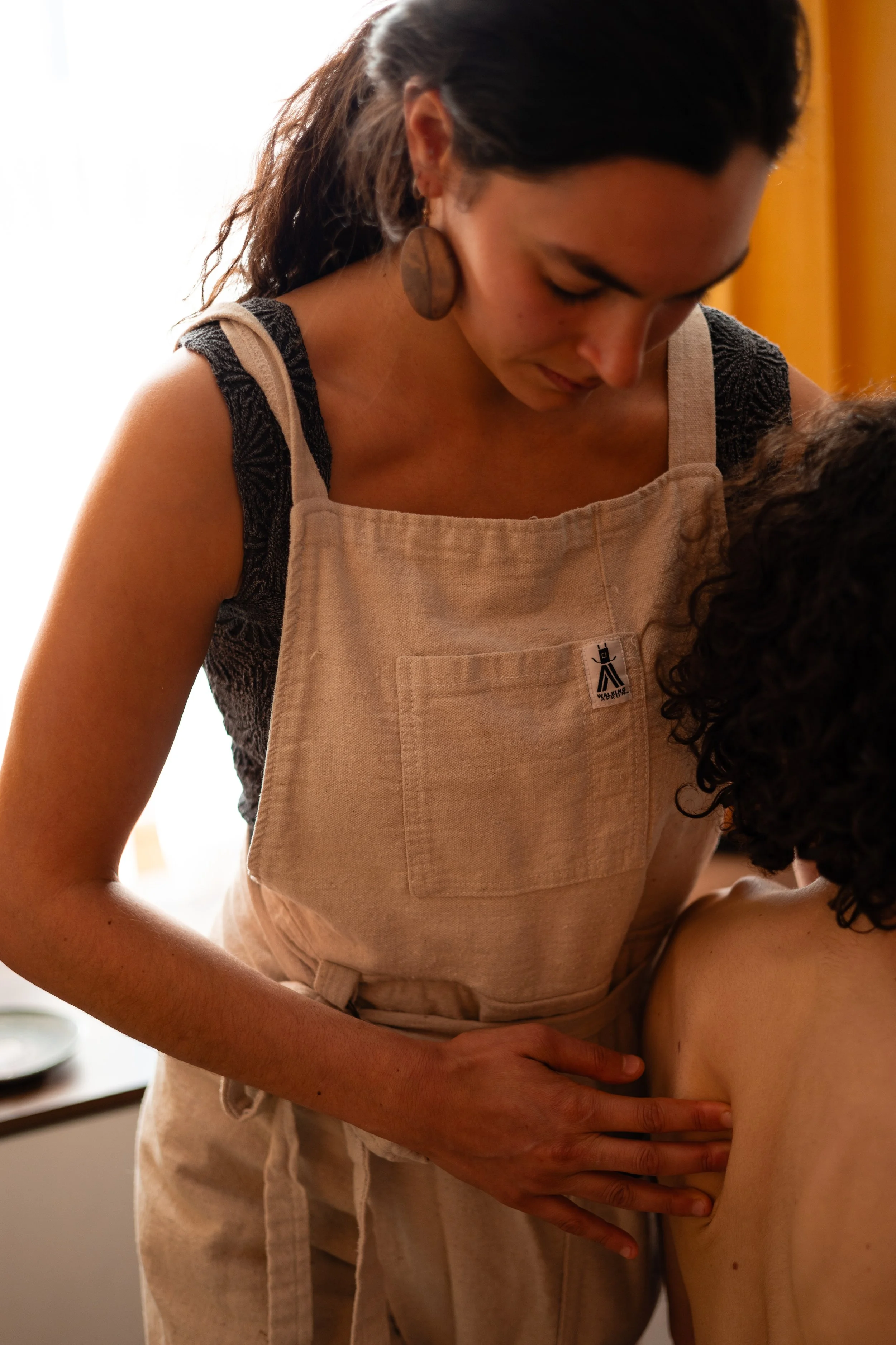 A woman in a beige apron giving a massage or acupuncture to a person's back.