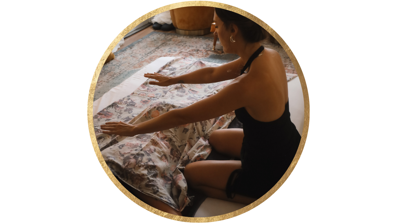 A woman practicing yoga or stretching on a floral-patterned cloth on the floor, sitting on her knees with arms extended forward.