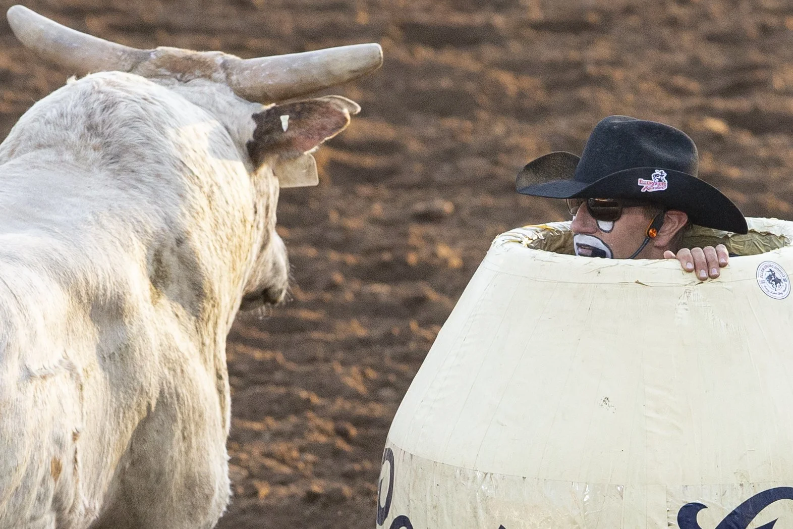 A bull passes by JJ Harrison as he shelters inside a barrel during competition.