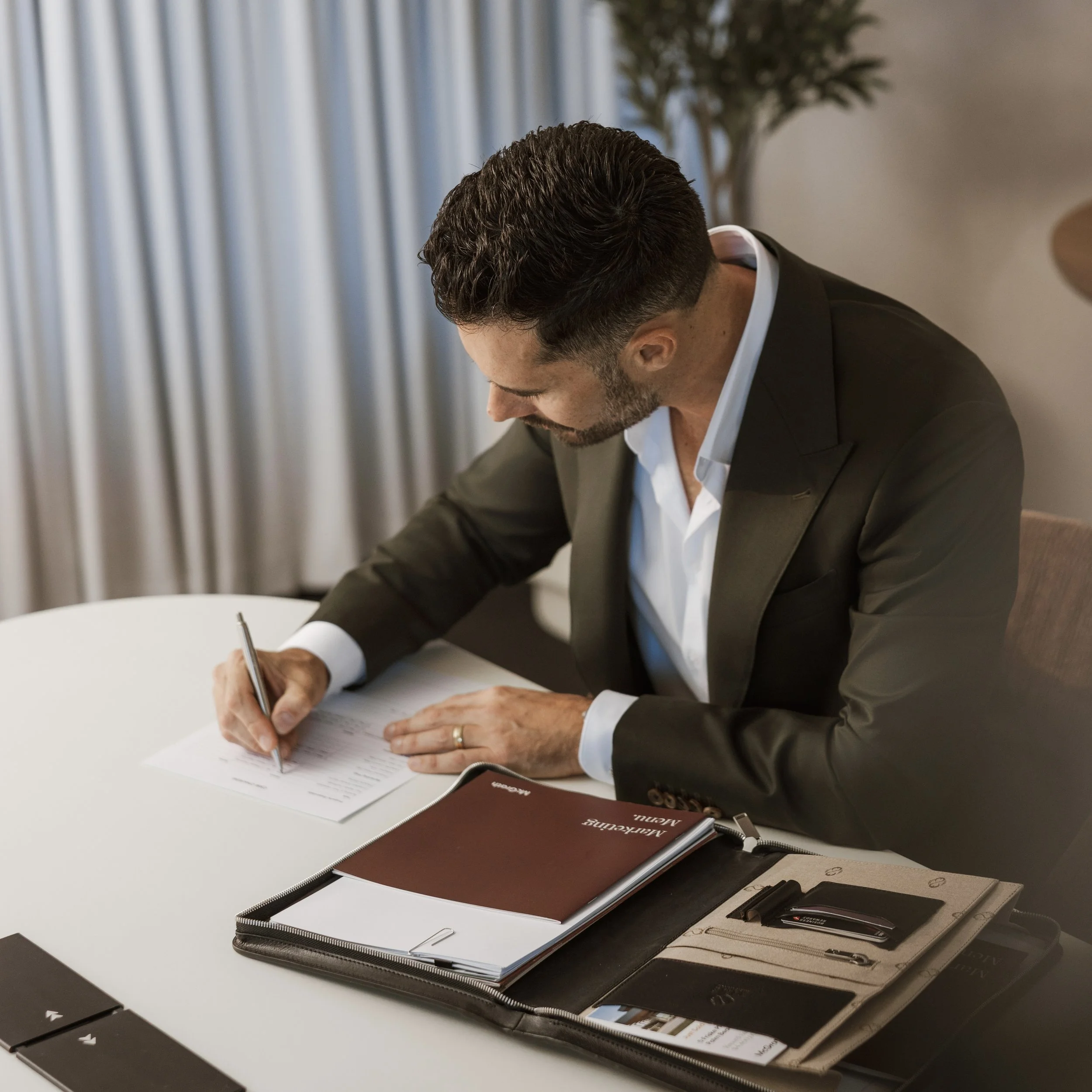 Businessman in a suit signing documents at a conference table