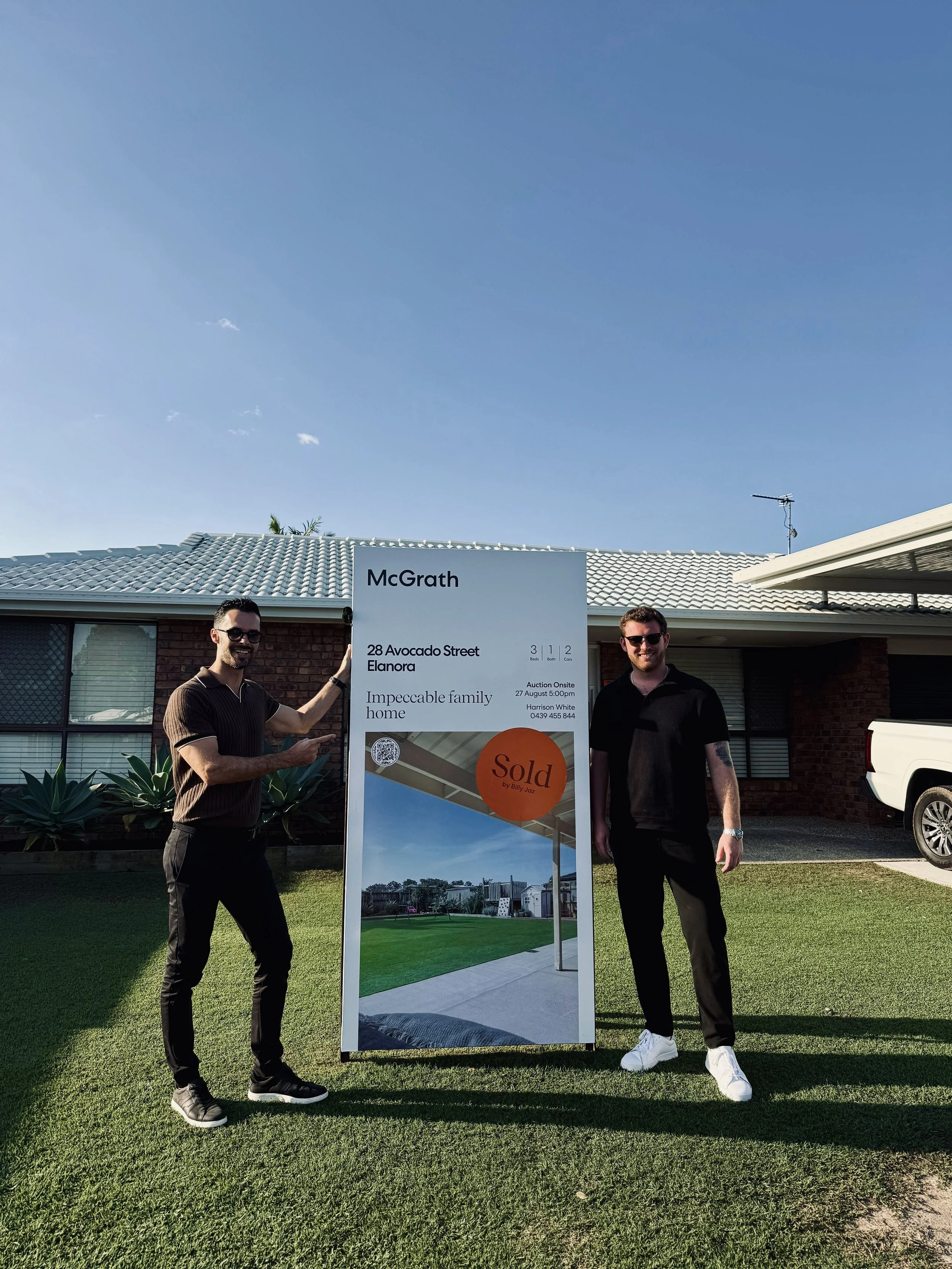 Billy Jaz and Harrison White standing next to a sold sign at 28 Avocado Street, Elanora.