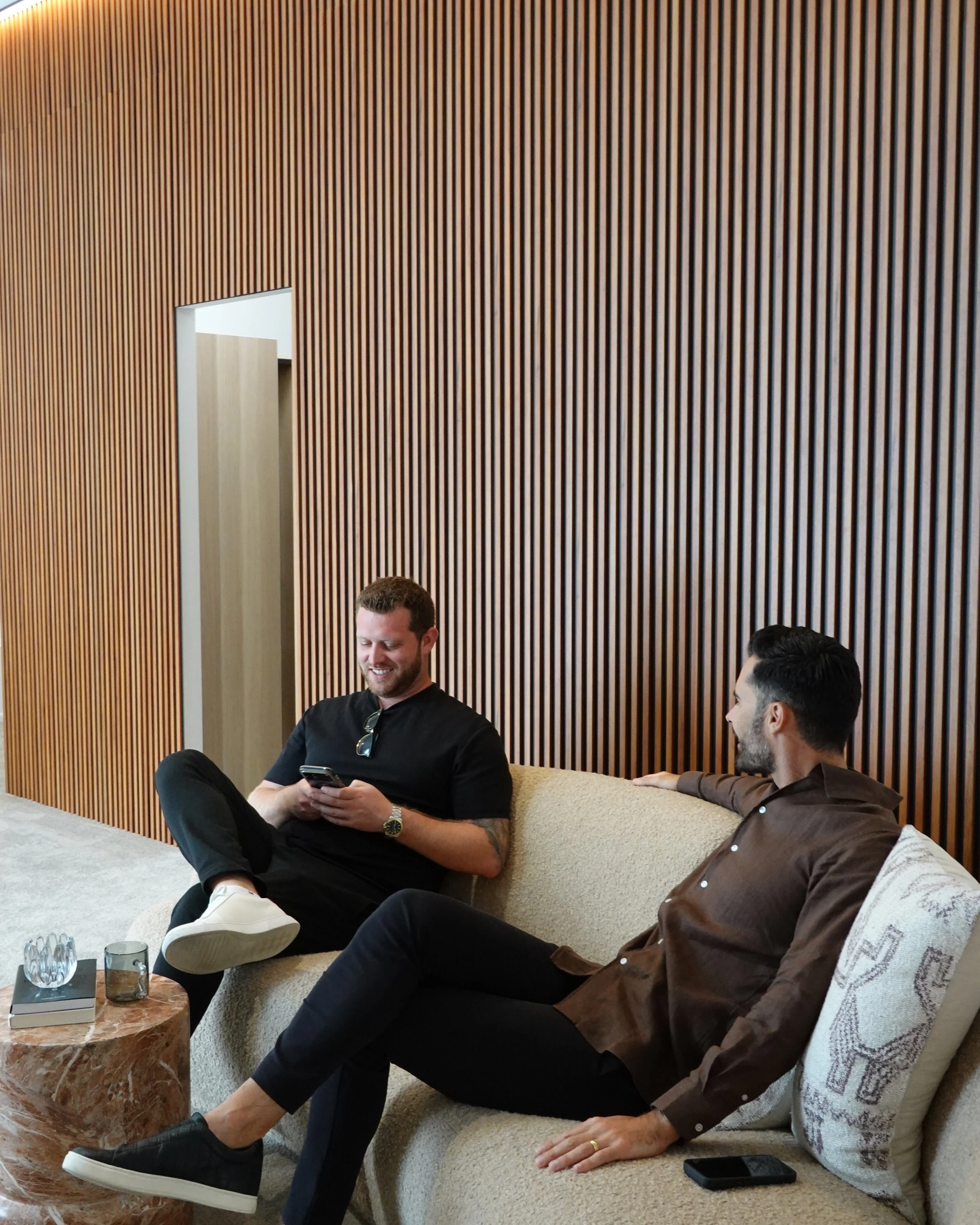 Harrison White and Billy Jaz on a couch discussing. Real Estate Agent. Prestige Property Market.