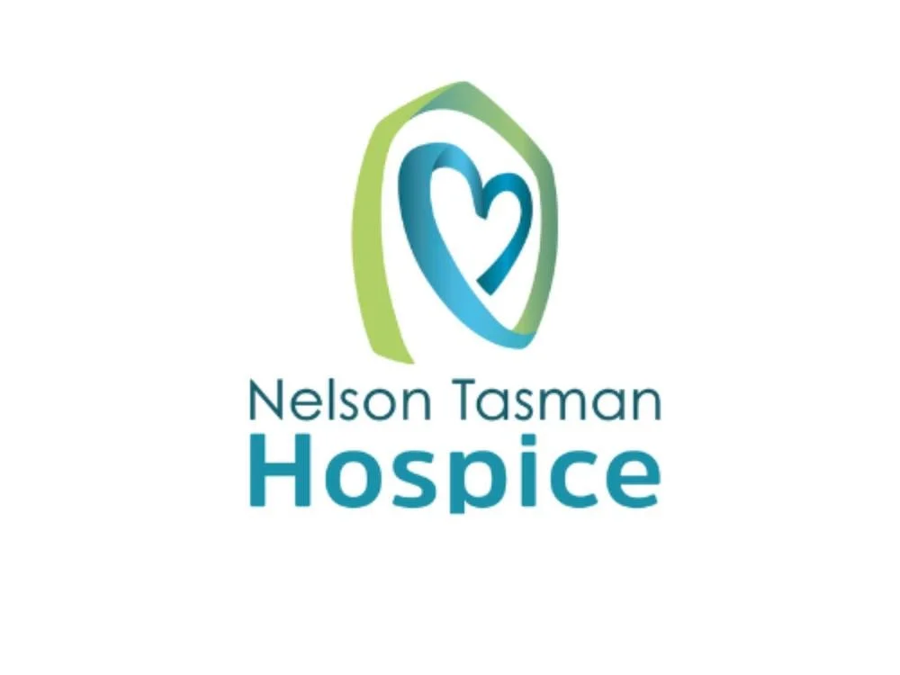 White background with green and blue Nelson Tasman Hospice text and a ribbon in the shape of a heart above the text