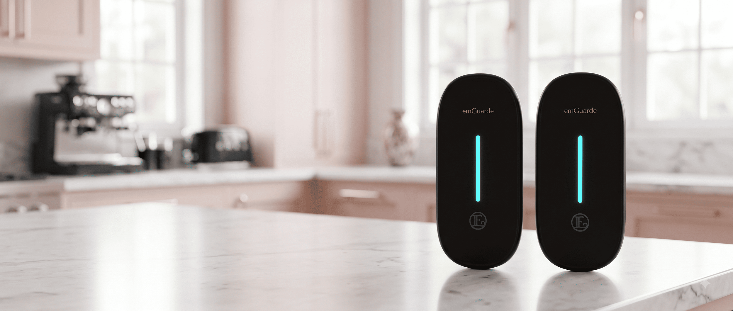 Set of two Enagic EmGuarde Go portable EMF harmonizers in matte black on a luxury kitchen countertop.