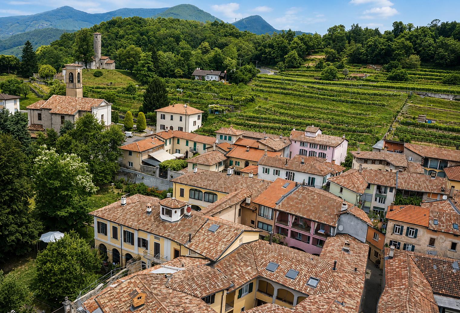 Photo of a hillside village with buildings that have terracotta tile roofs, surrounded by lush green trees and terraced agriculture on the hillside, with mountains in the background.
