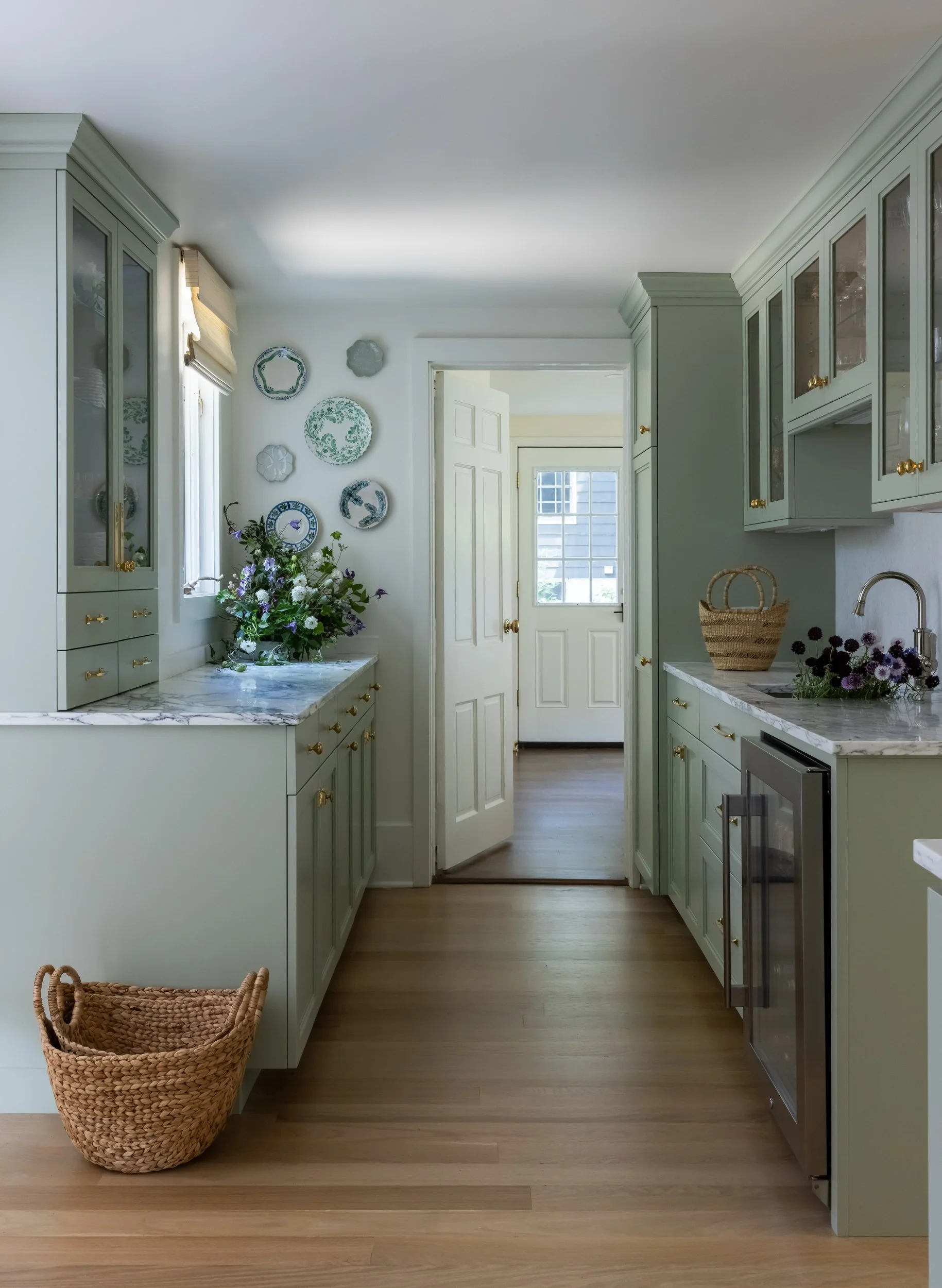 Narrow white kitchen galley with wood floors by Raquel Langworthy