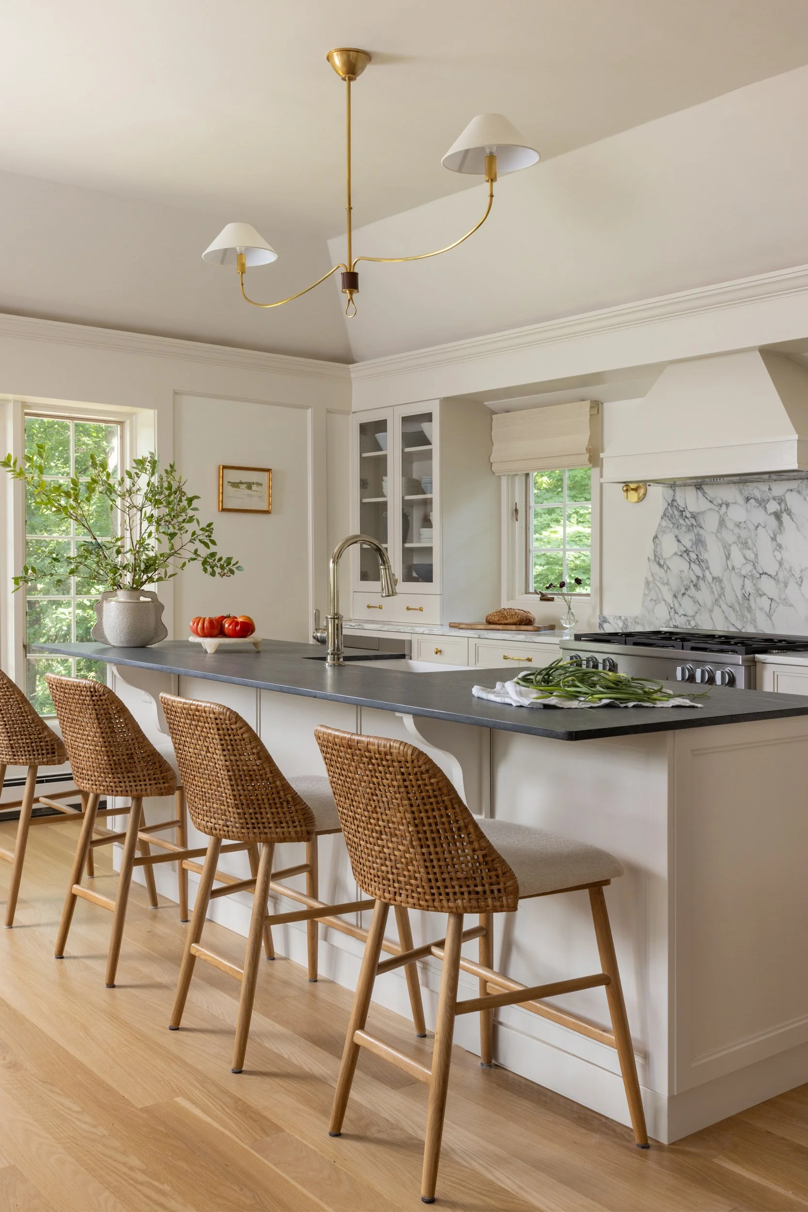 Bright white kitchen with bar stools and pendant lights by Raquel Langworthy