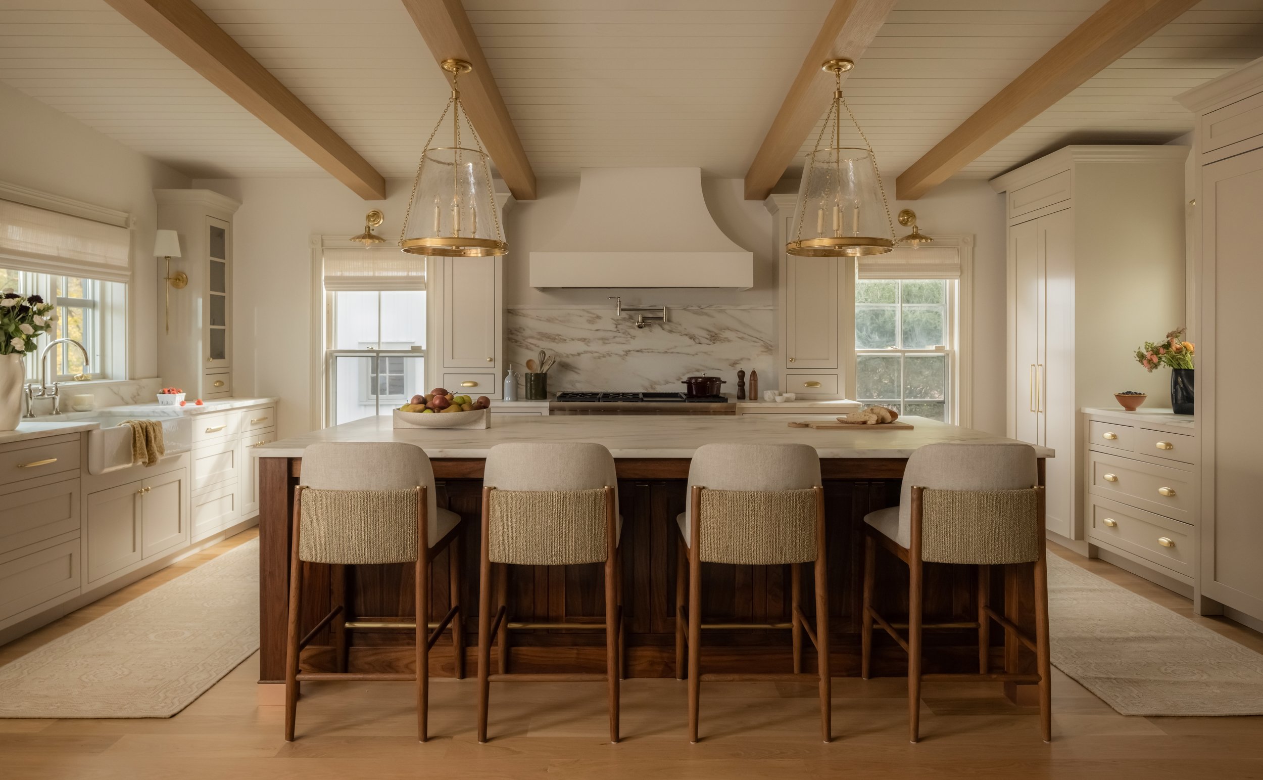 Warm, neutral kitchen with architectural wood beams and natural light, as featured in The Wall Street Journal. Photographed in Roslyn, NY, by Raquel Langworthy