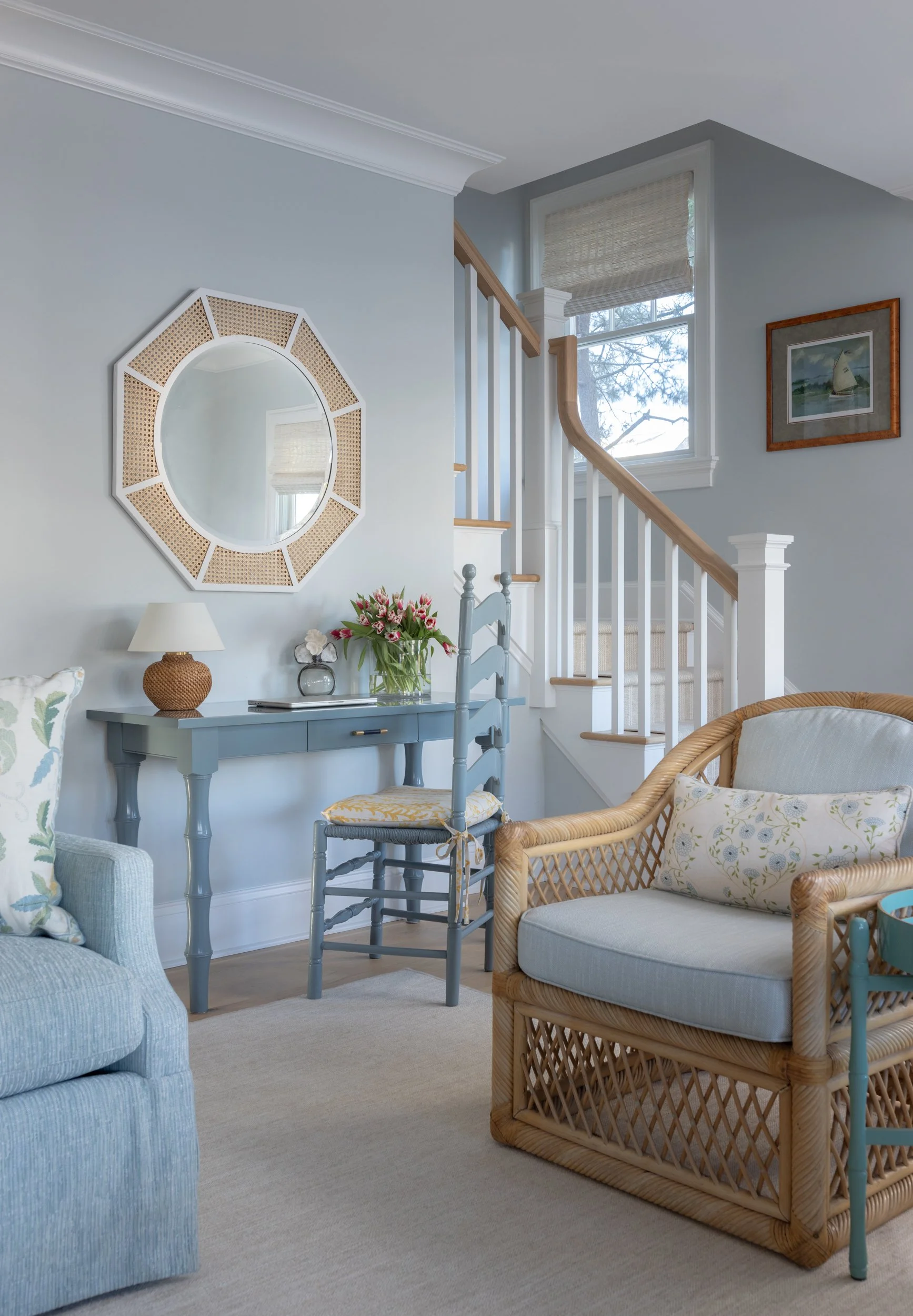 Blue living room with staircase and round mirror by Raquel Langworthy