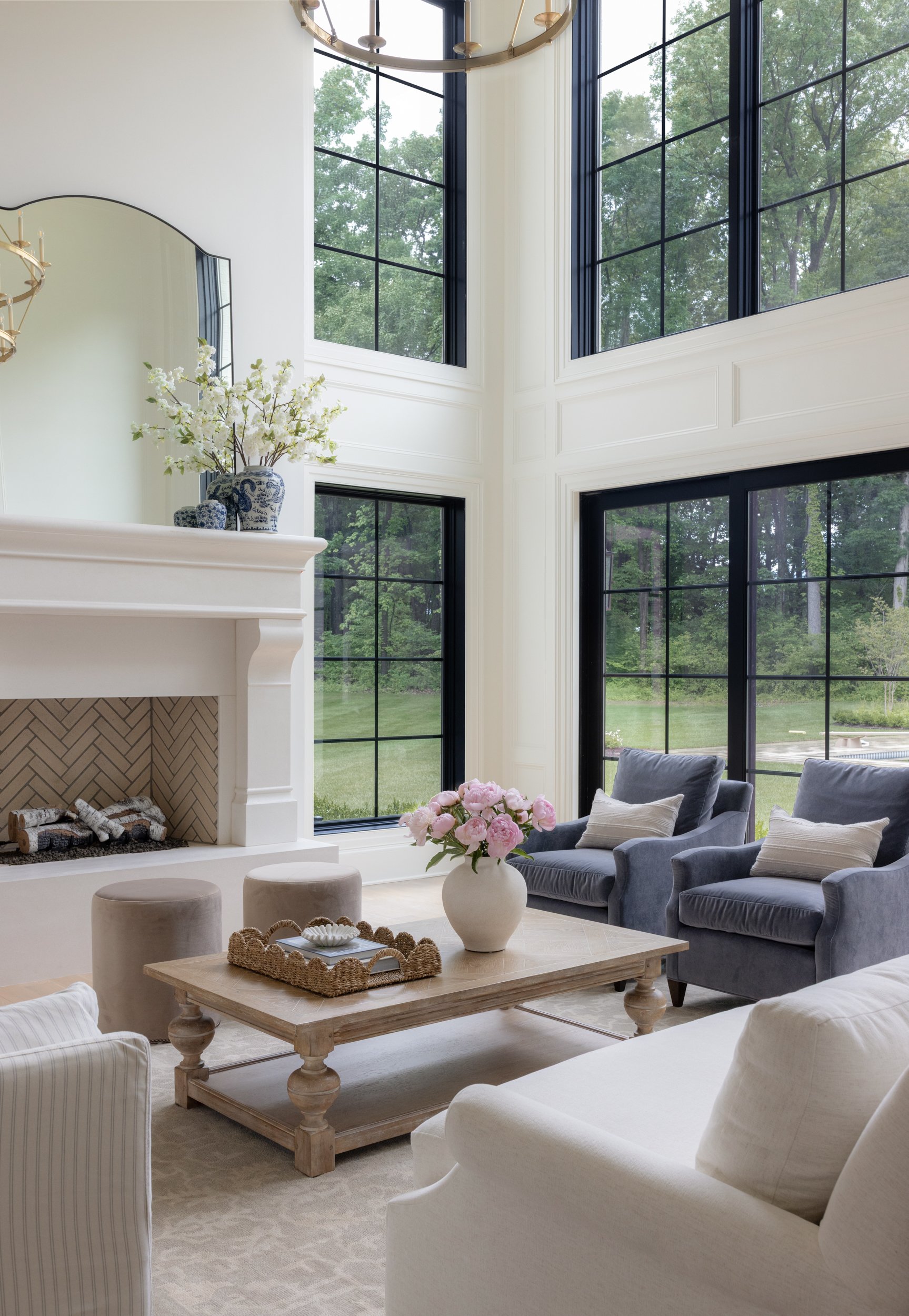 Bright double height living room with large windows by Raquel Langworthy