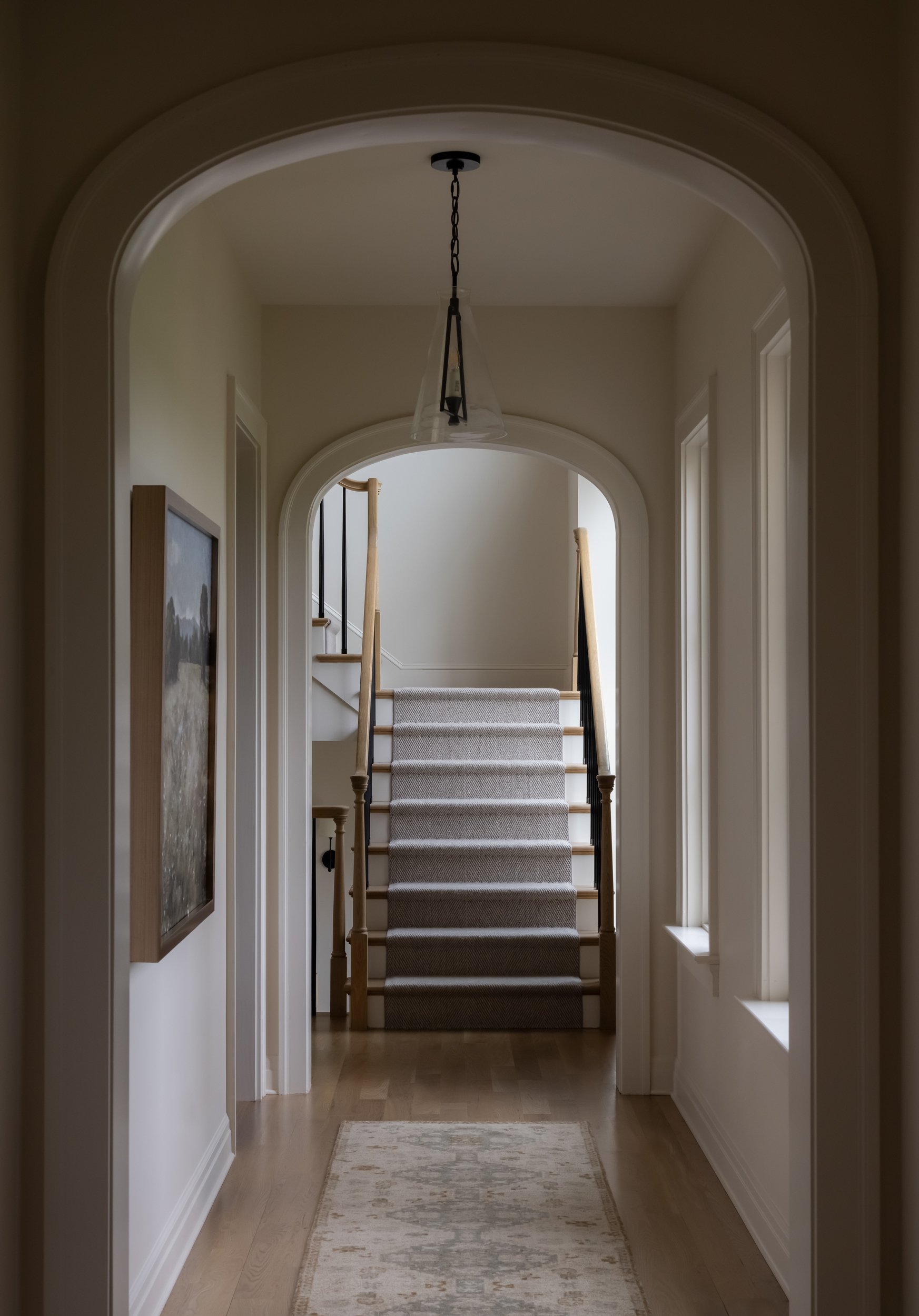 Elegant arched hallway with staircase by Raquel Langworthy