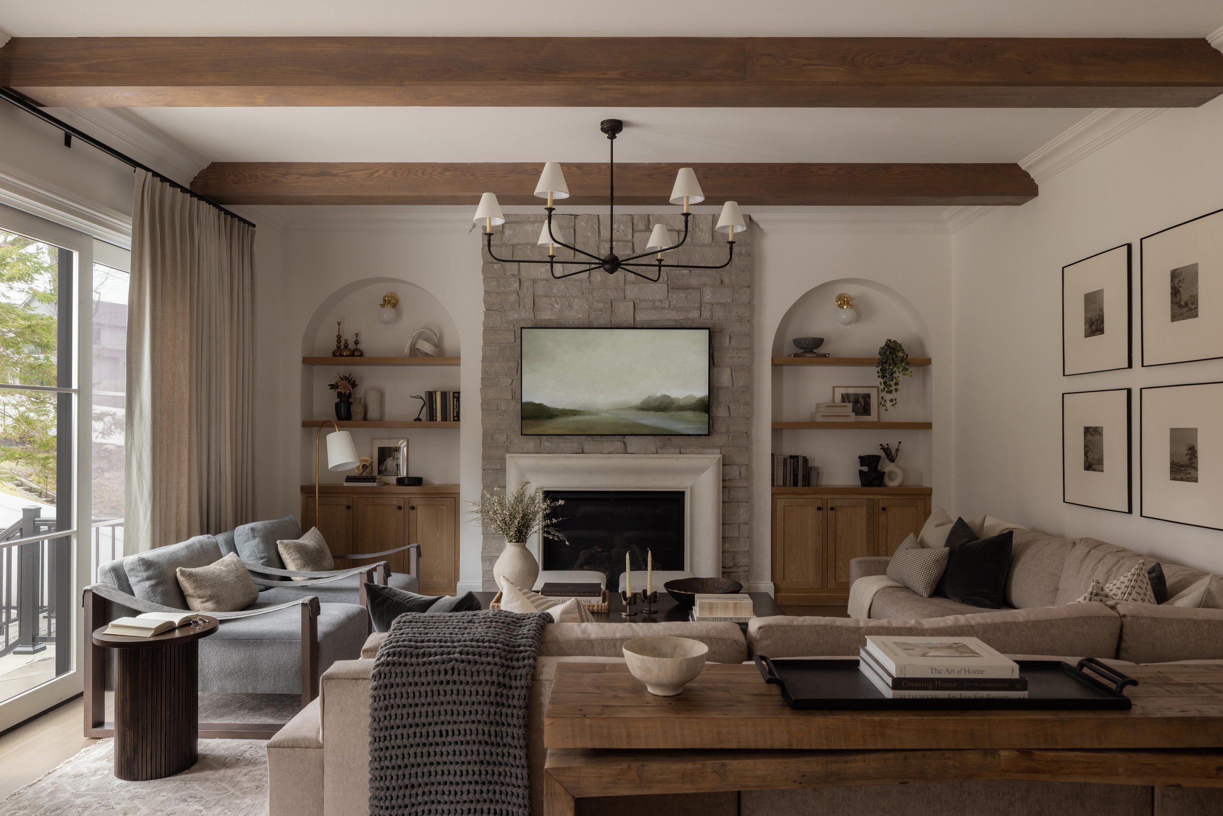 Rustic living room with arched fireplace and chandelier by Raquel Langworthy