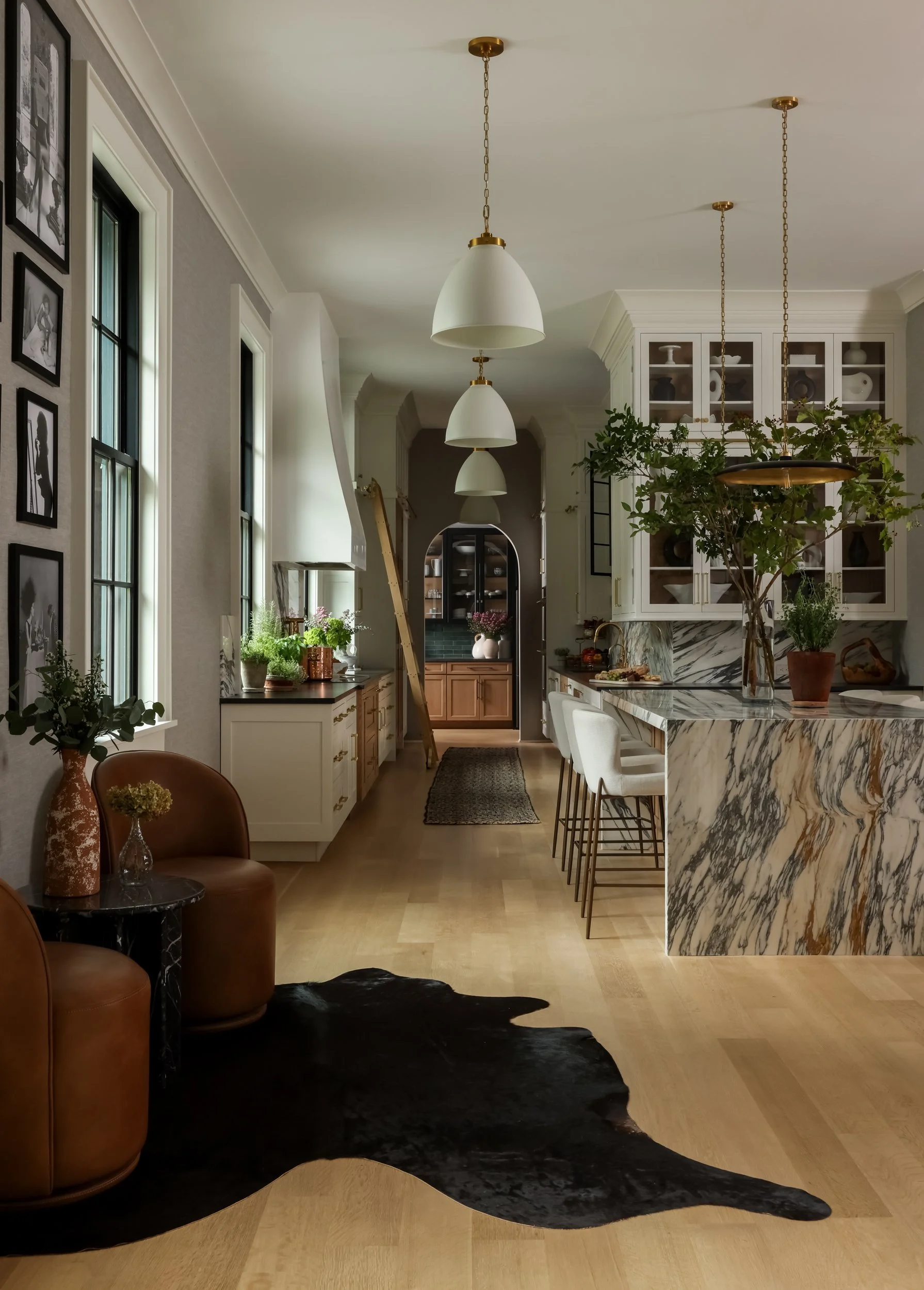 Bright white hallway with pendant lights and cowhide rug by Raquel Langworthy