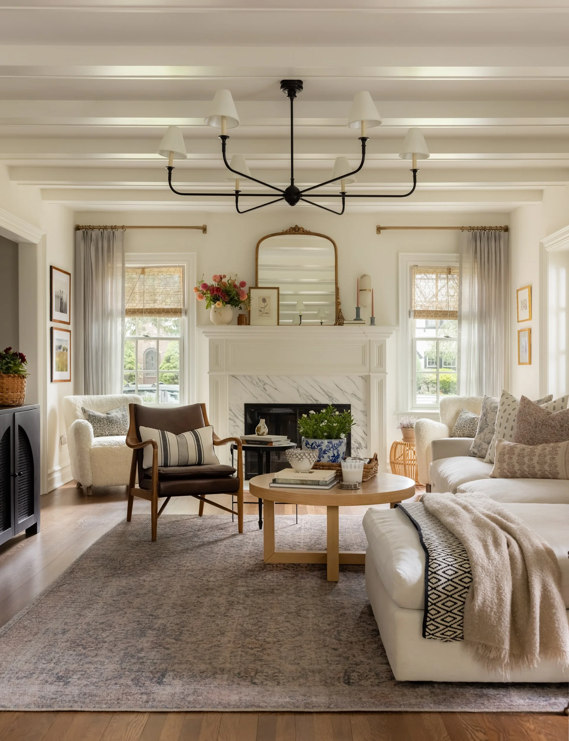 Living room with black chandelier and stone fireplace by Raquel Langworthy