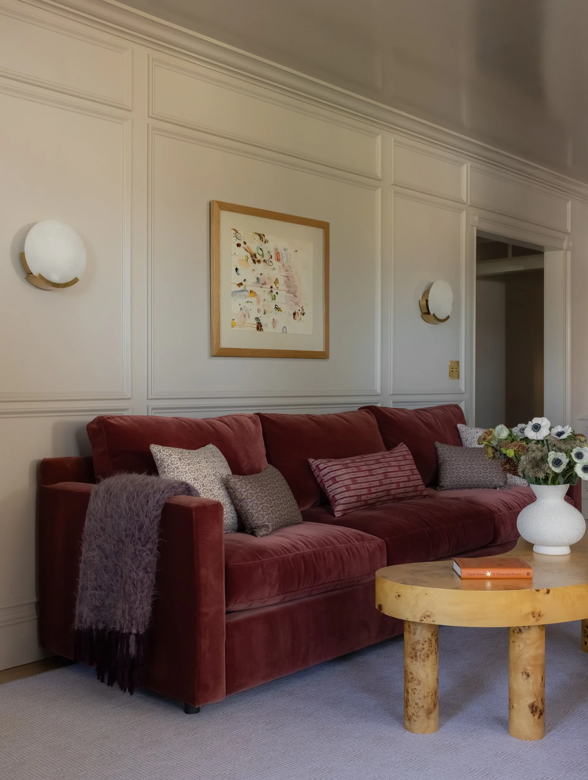 Cozy living room with burgundy sofa by Raquel Langworthy