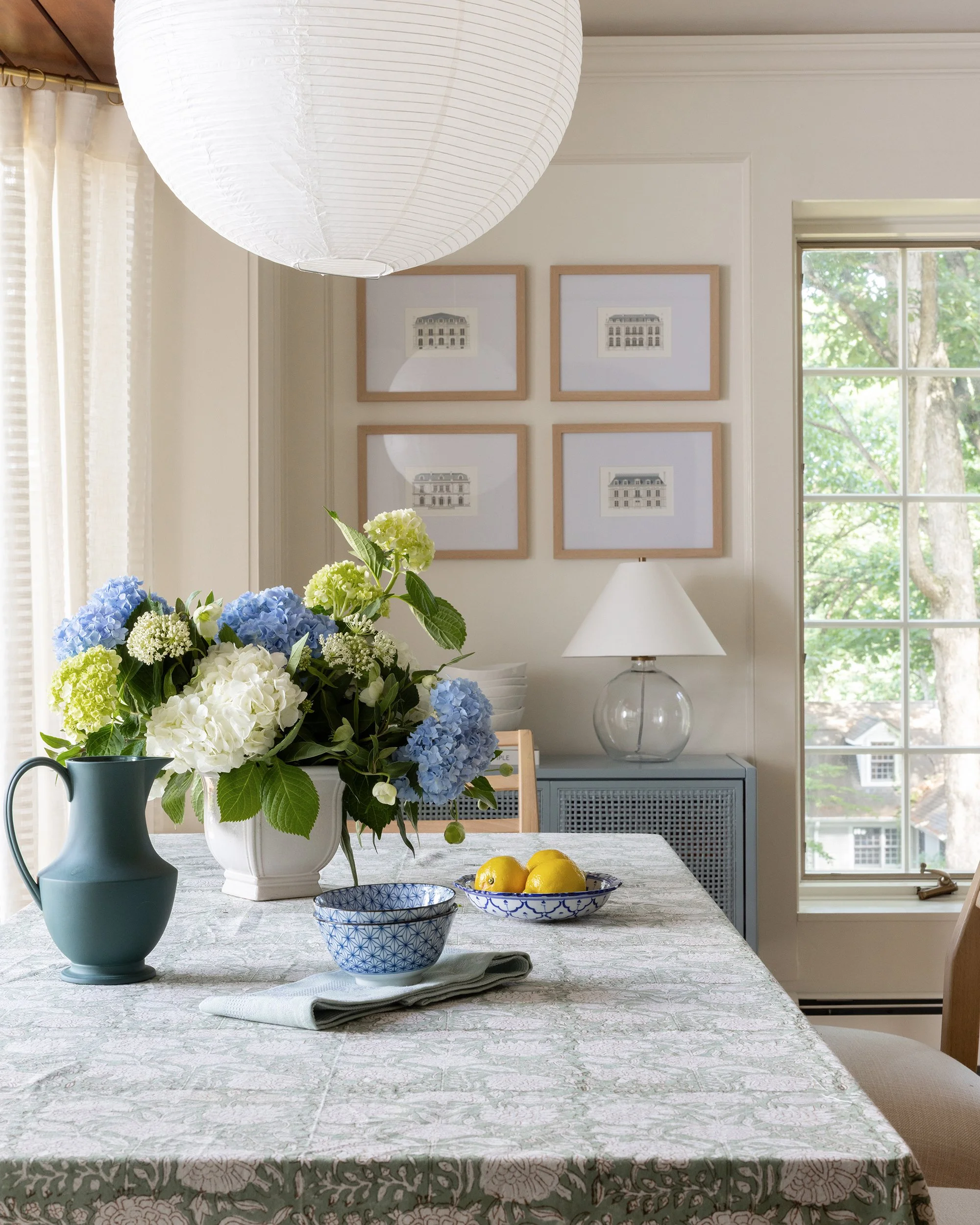 Dining table with blue floral arrangement and framed art by Raquel Langworthy