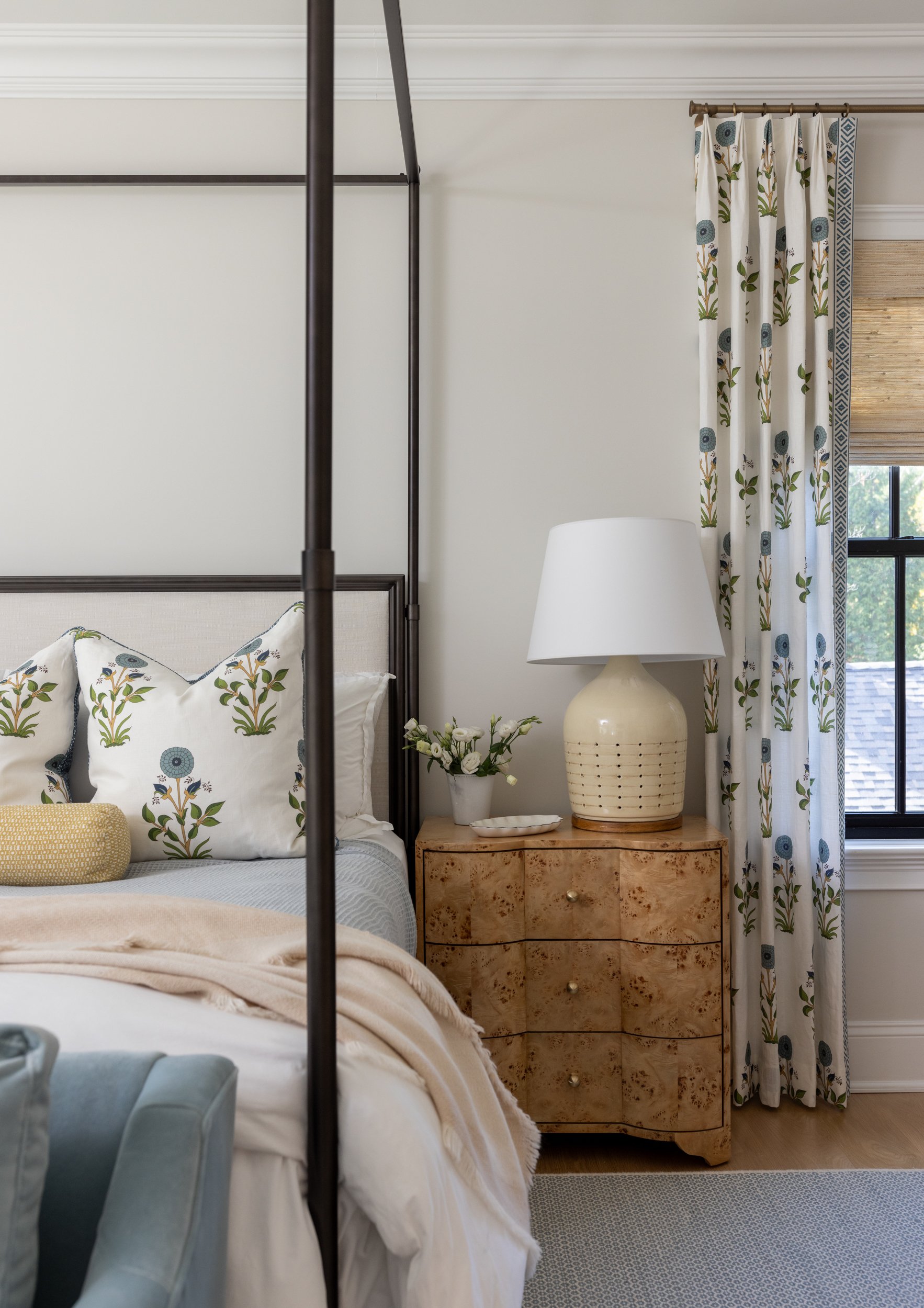 Elegant bedroom with floral curtains and wood nightstand by Raquel Langworthy