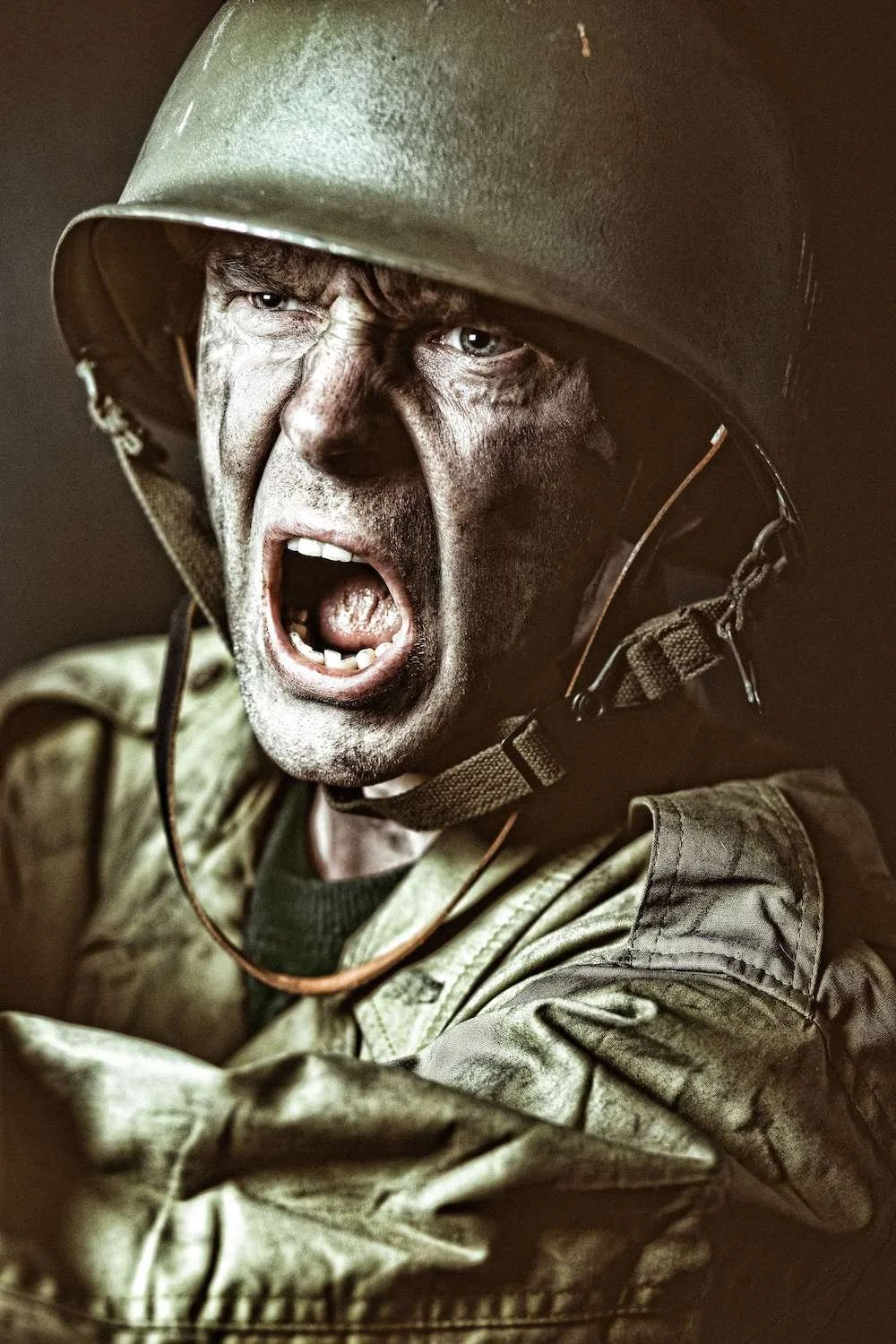 A male soldier wearing military army clothing expressing anger whilst shouting or screaming as he prepares to fight in battle