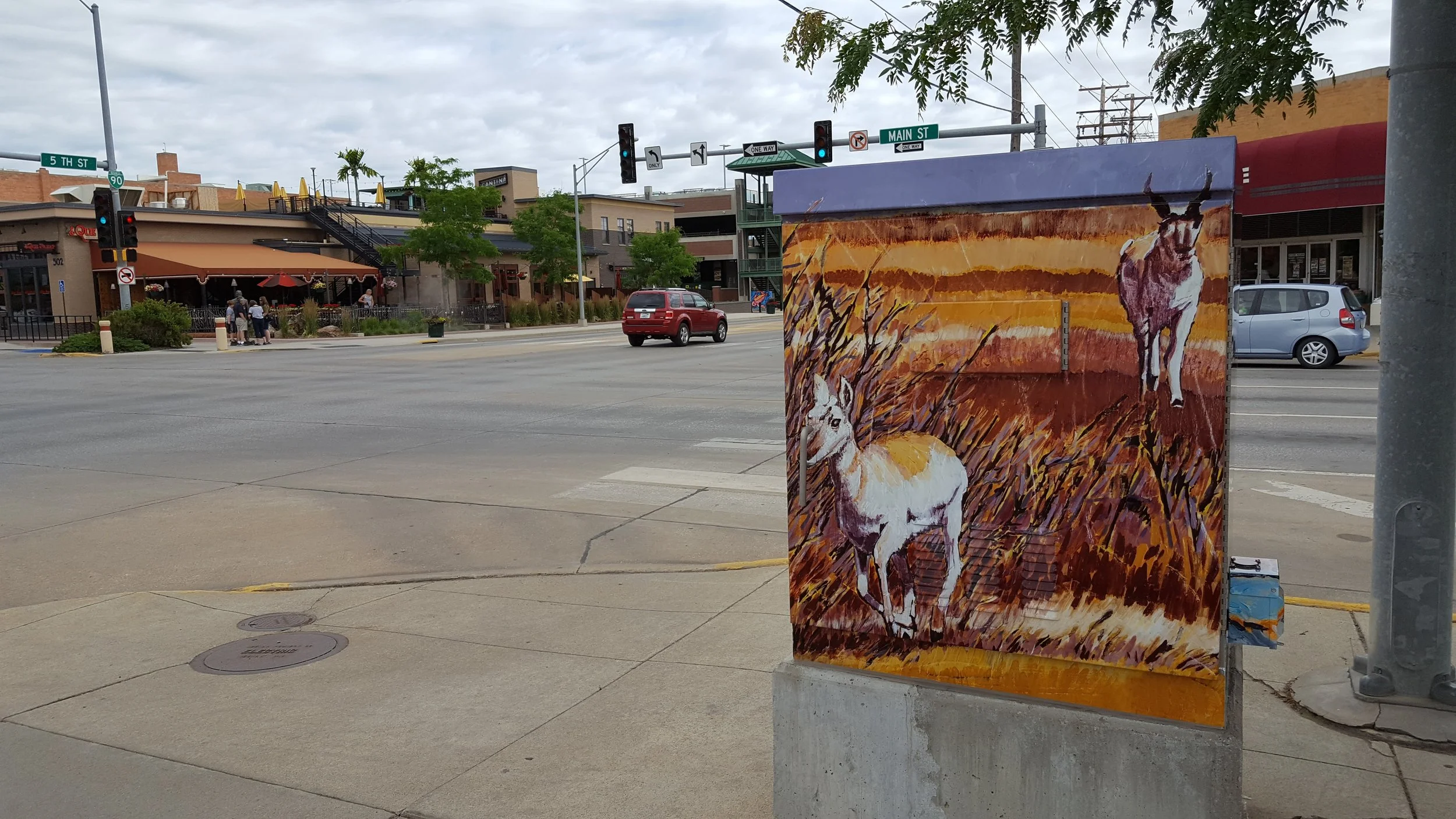 Rapid City utility box art featuring a pronghorn standing in tall prairie grass with another animal in the distance.