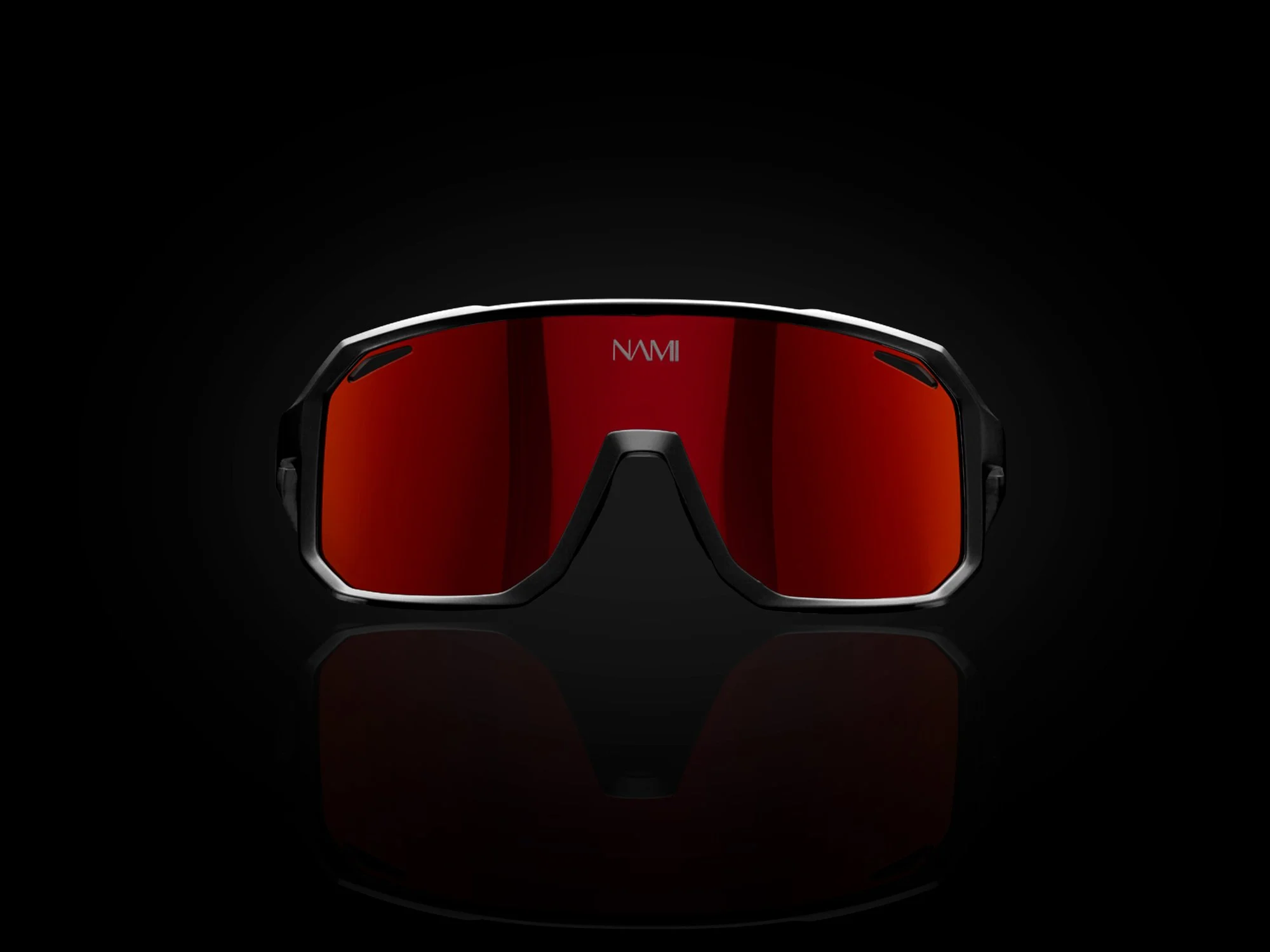Close-up of a black sports sunglasses with red reflective lenses against a dark background.