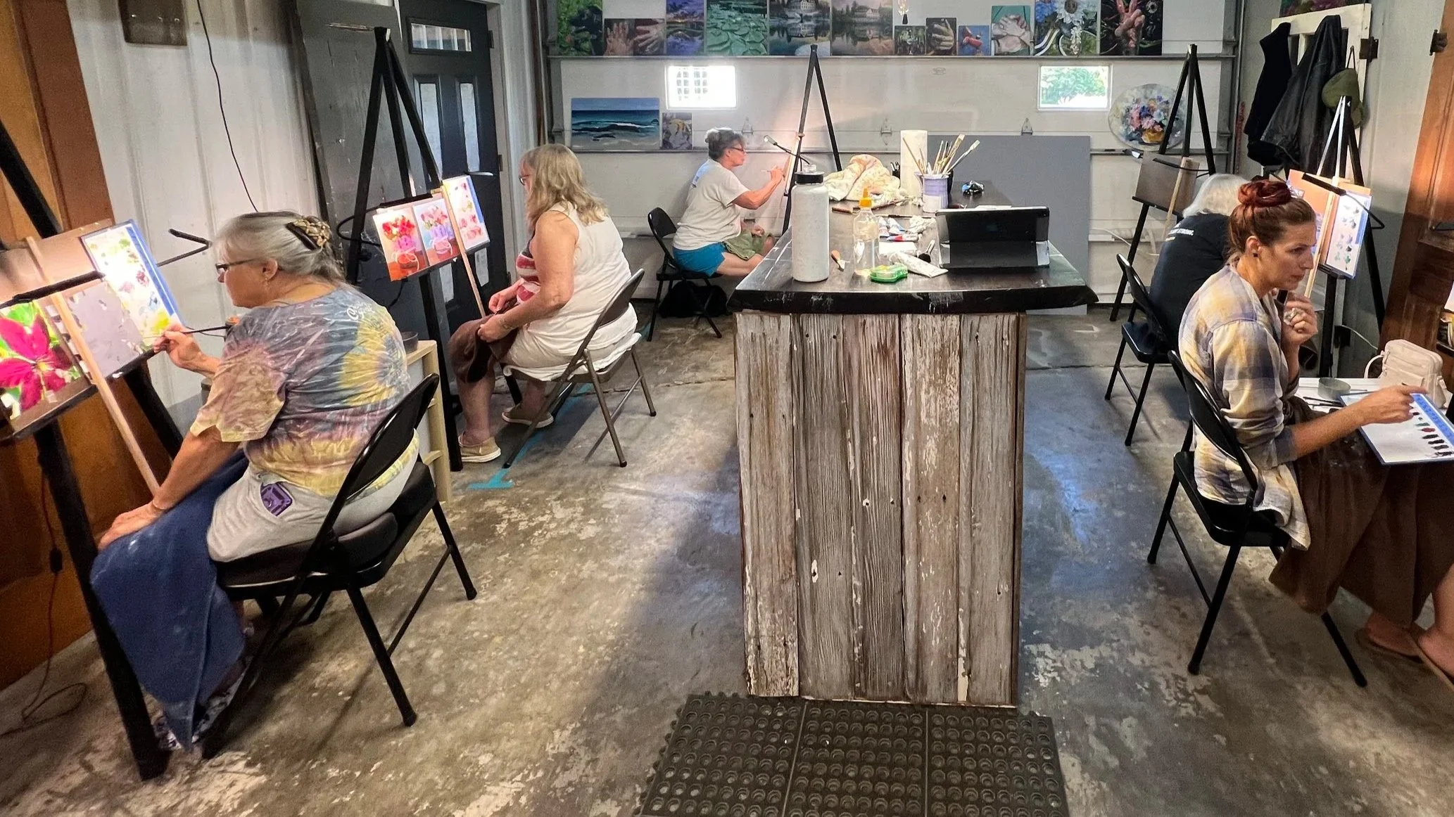 Students painting on individual canvases in an art studio classroom.