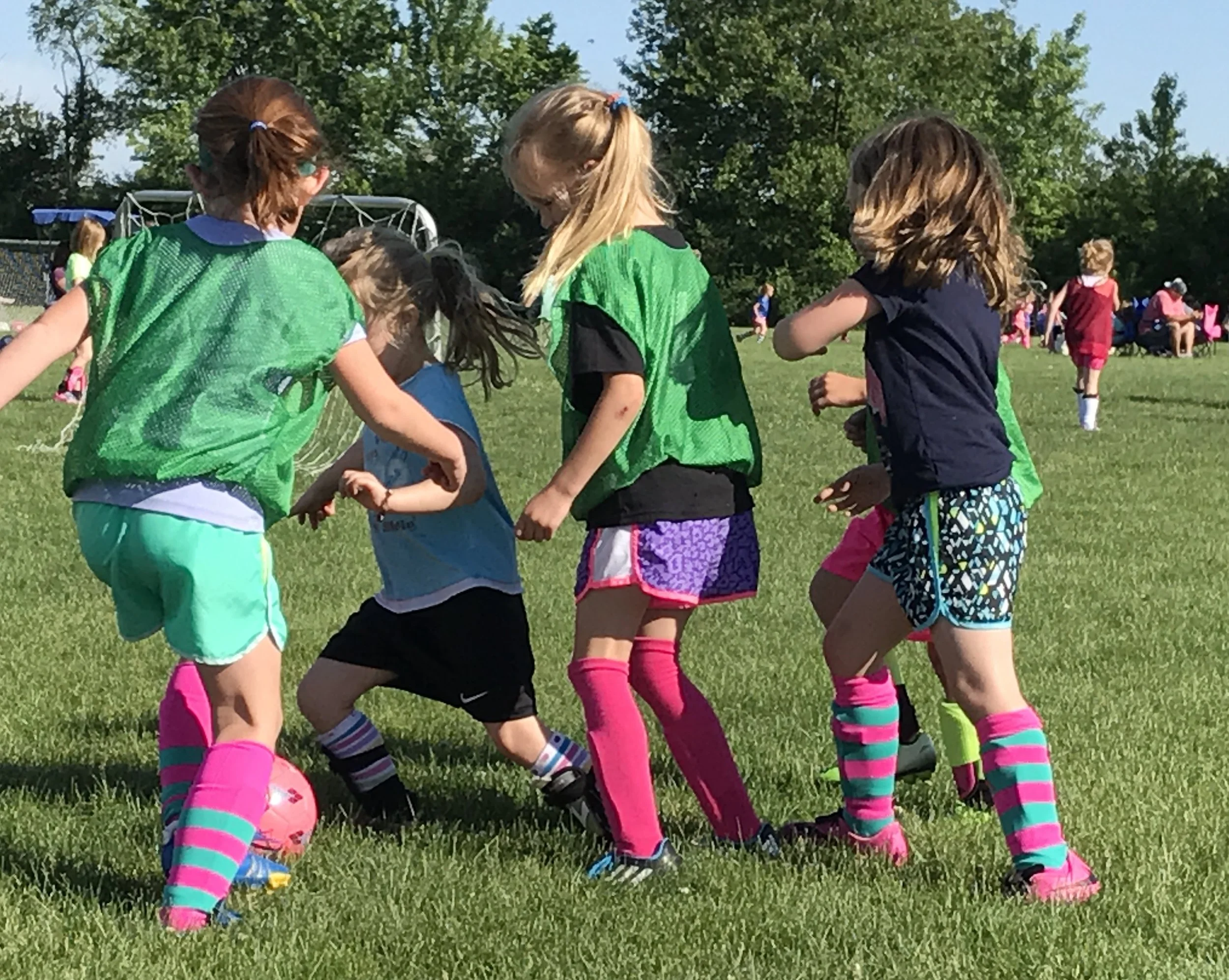 Six-year-old girls playing soccer illustrating the “everyone chases the ball” metaphor for a growing organization.